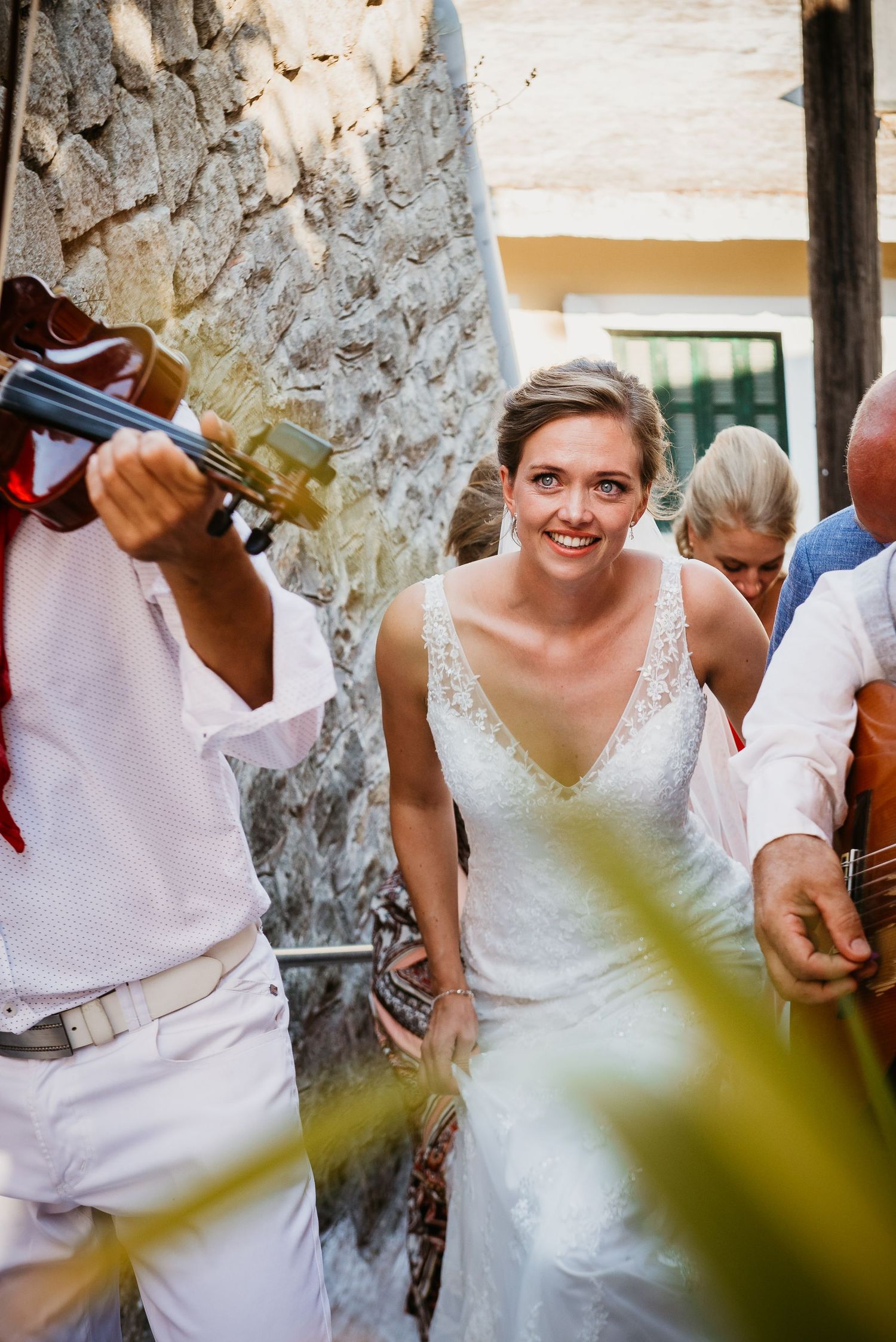 White wedding dress flowing in the breeze against a rustic stone wall backdrop.