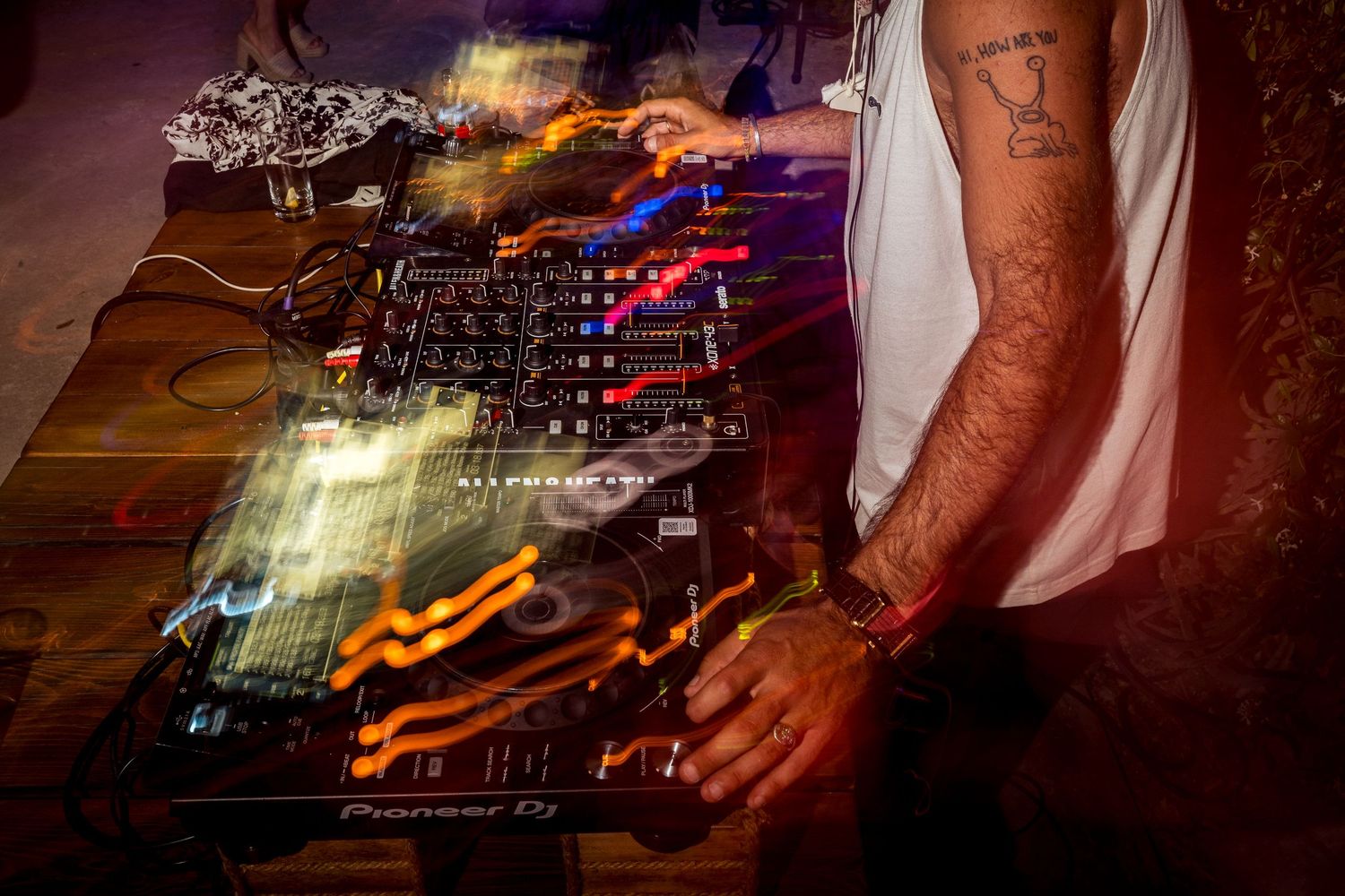 Close-up of DJ equipment and hands mixing music at nighttime event.