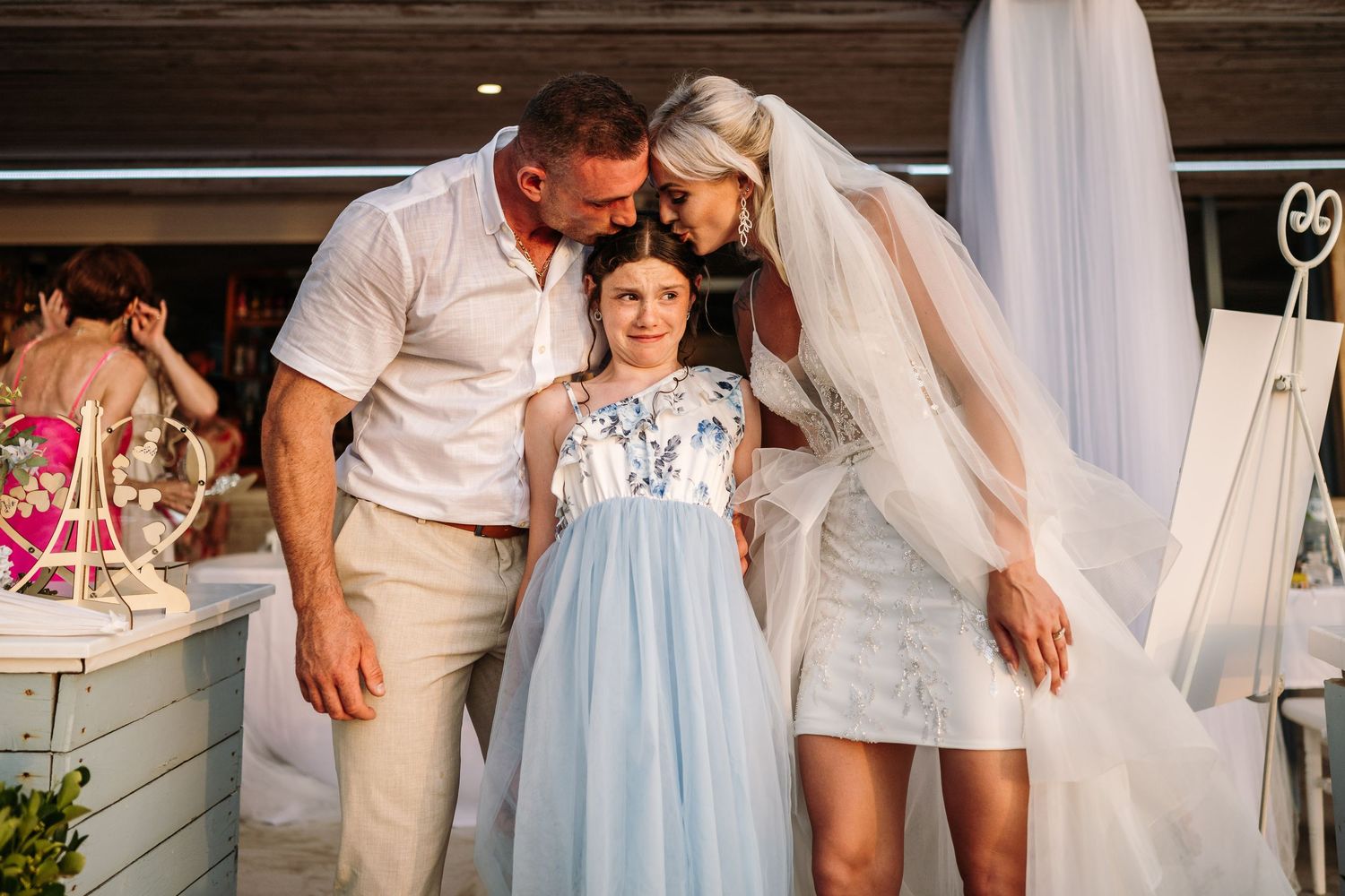 Elegant outdoor wedding reception with guests in white and pastel blue attire.