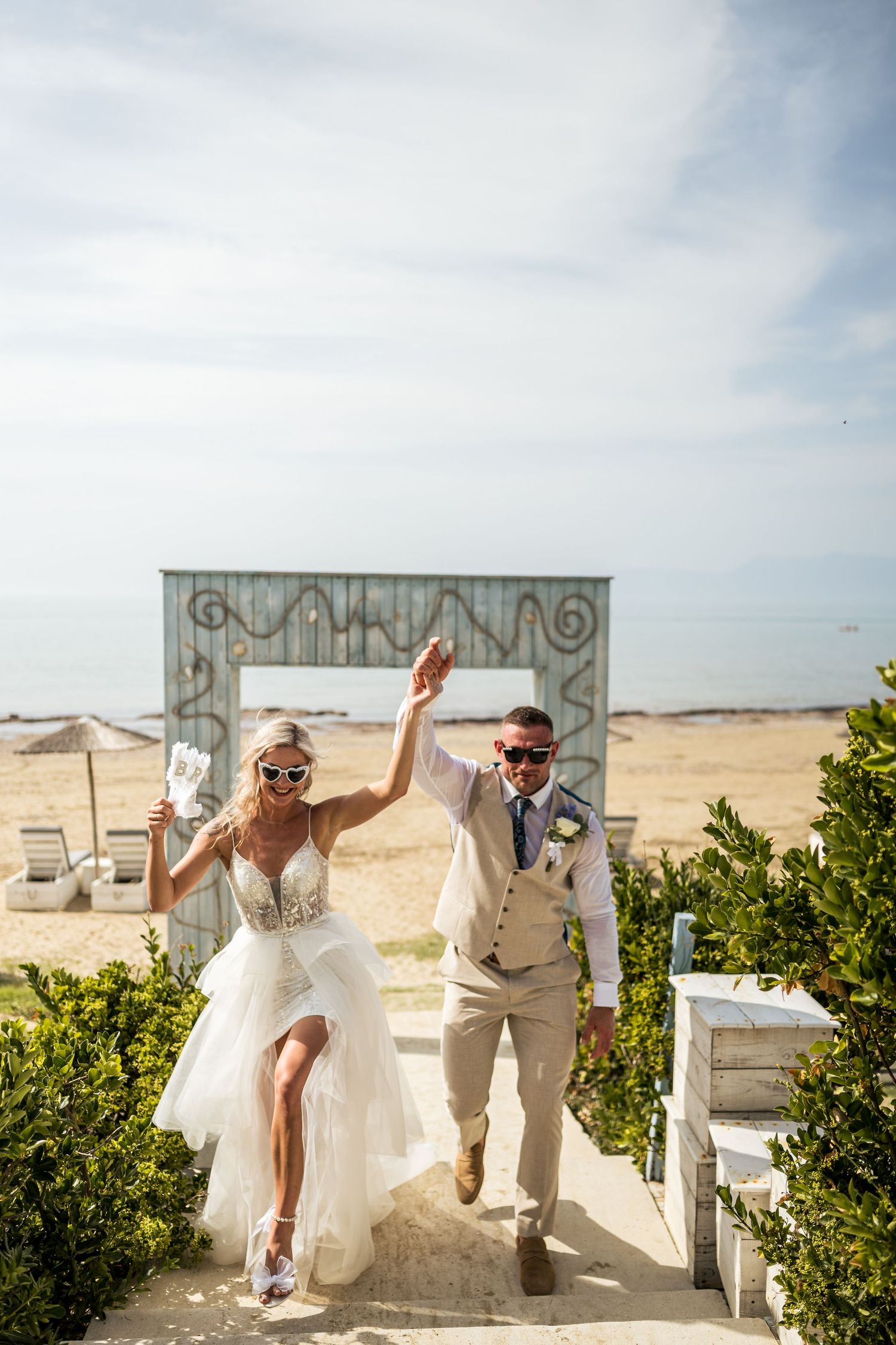 Celebratory exit down white steps at a beachside wedding venue.