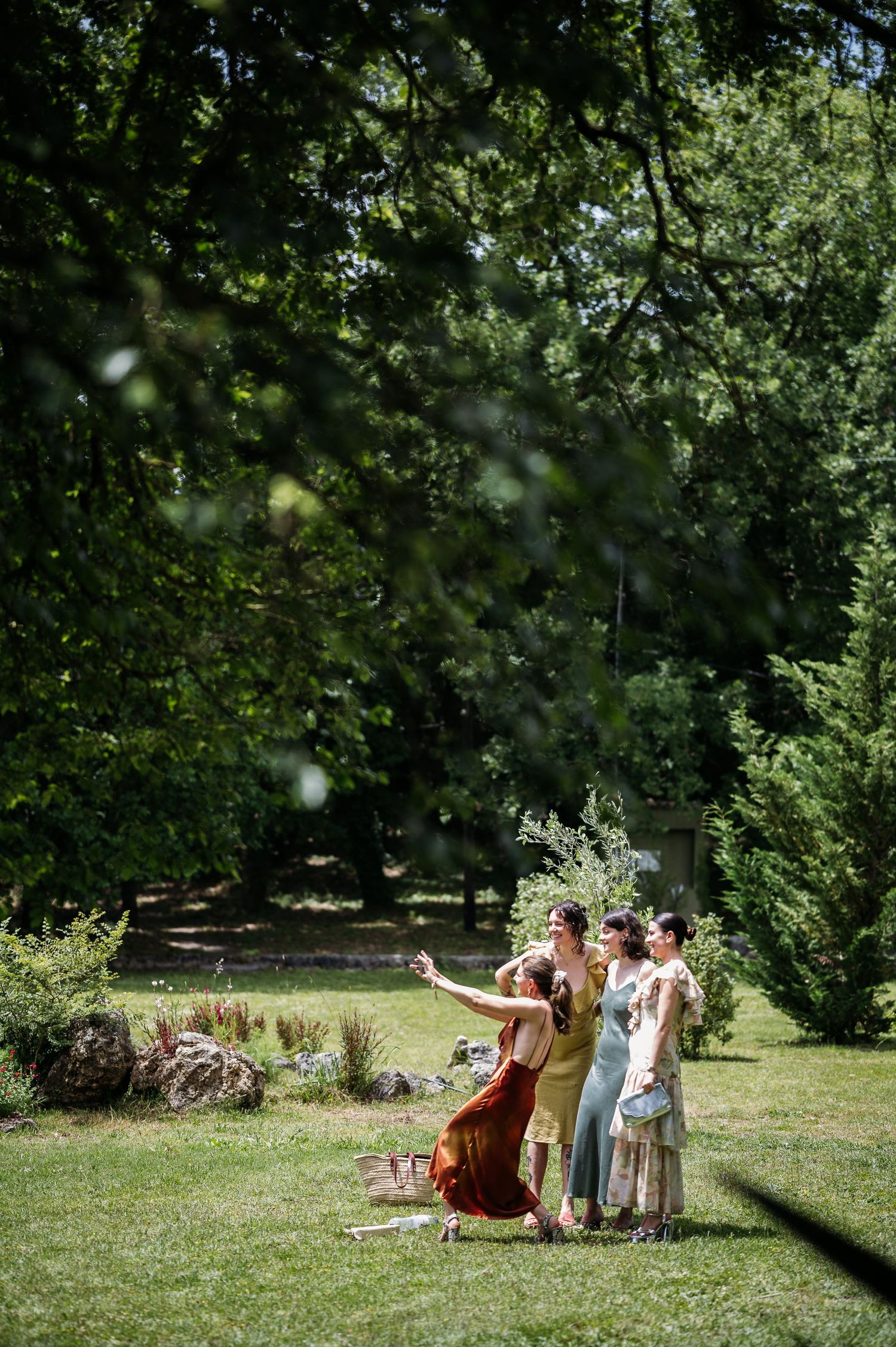 People relaxing on a grassy lawn surrounded by leafy trees on a summer day.