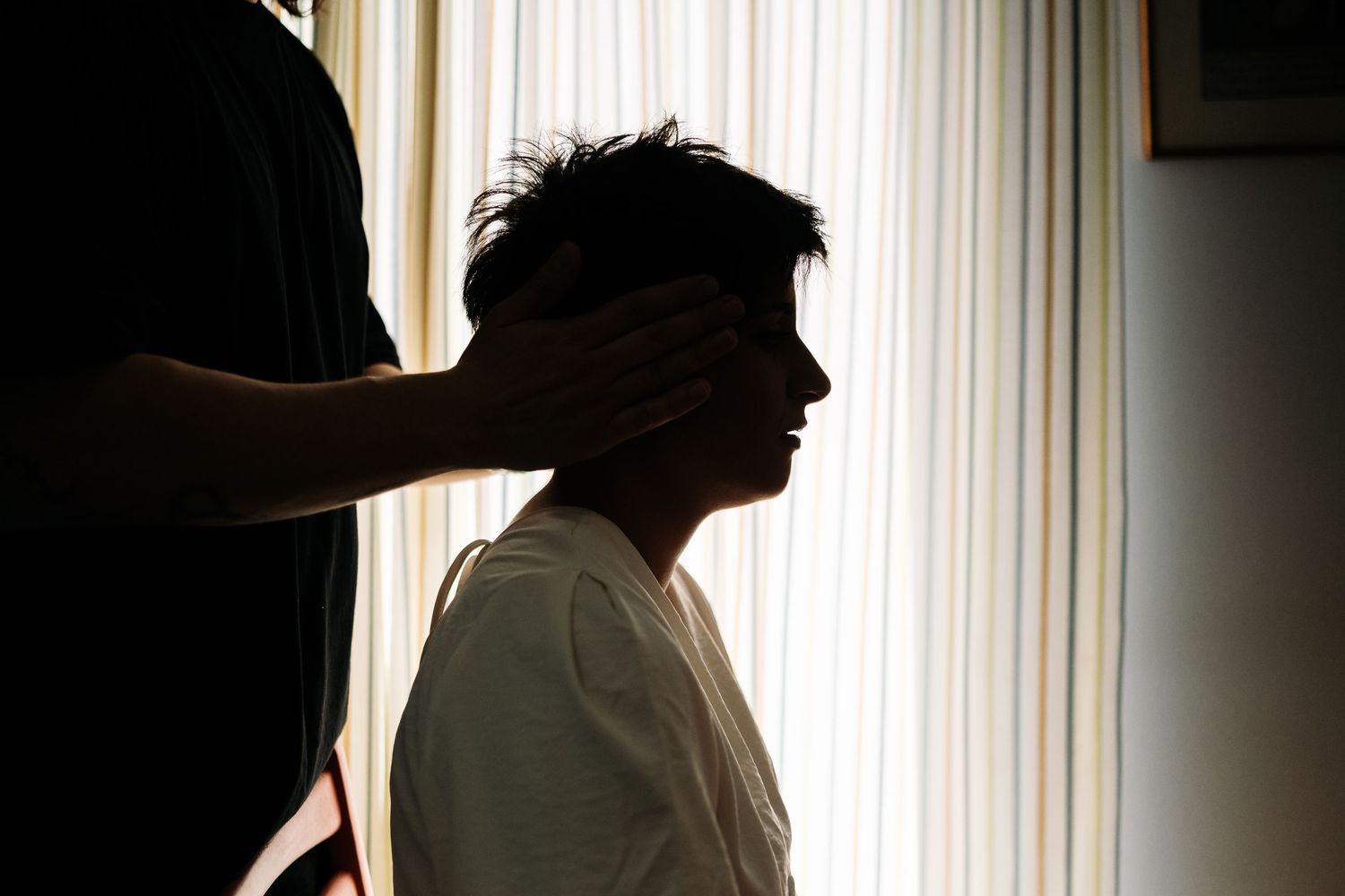 Silhouettes against window light during wedding preparation.
