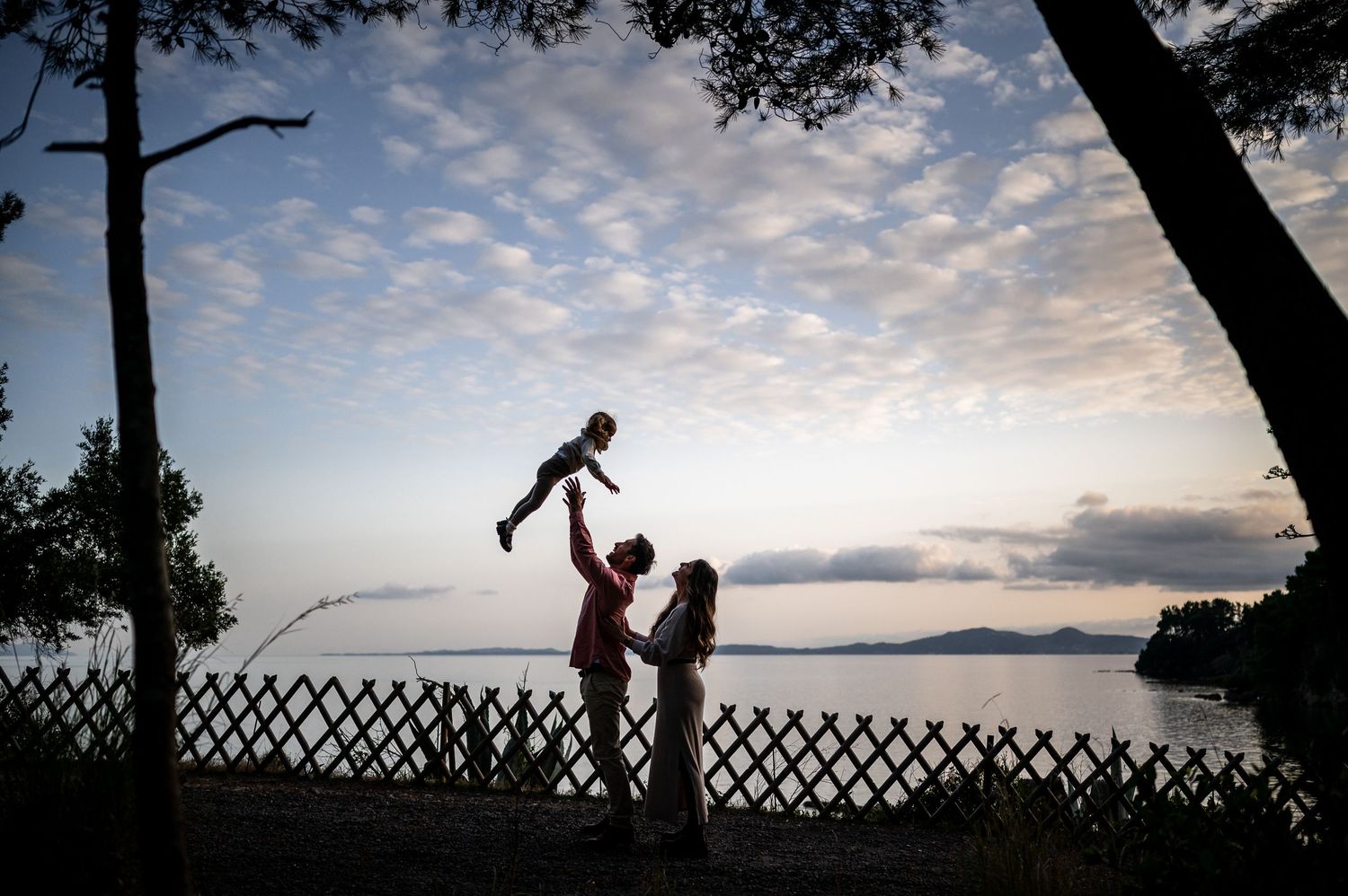 Silhouettes against a dramatic sunset sky framed by tree branches.
