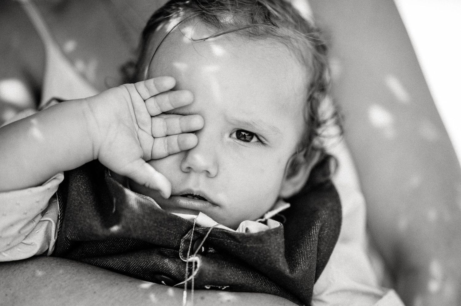 Close-up of a baby rubbing their eye during a baptism ceremony.