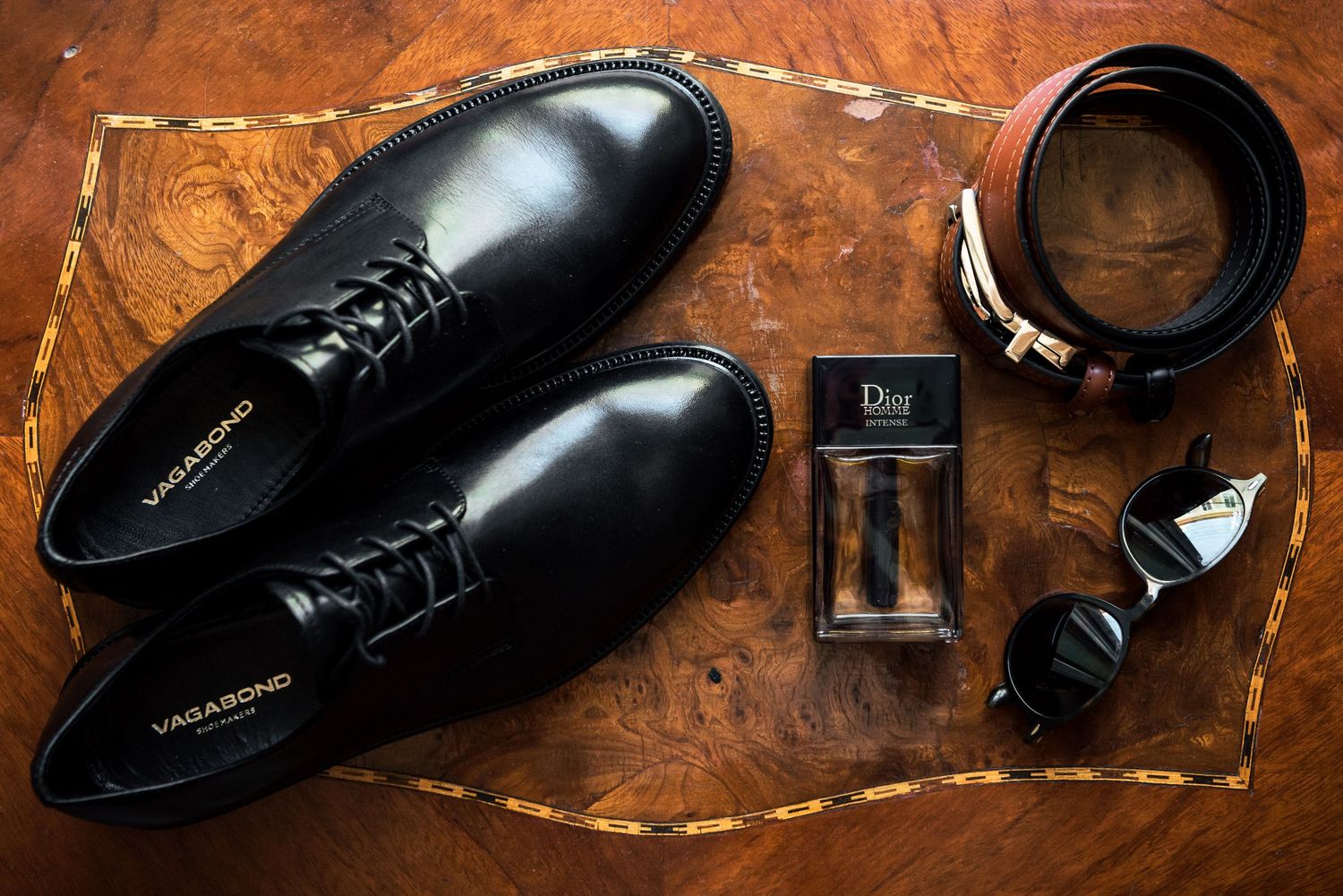 Elegant black leather dress shoes arranged on a rustic wooden surface with warm lighting.