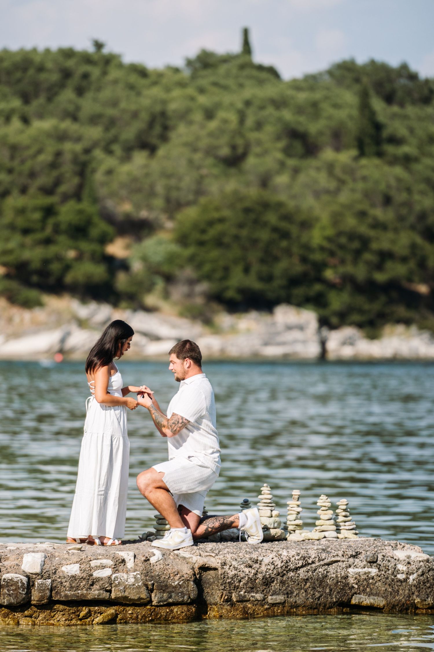 Romantic proposal setup on a rocky coastline with white candles.