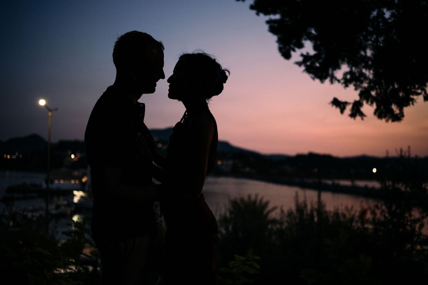 Silhouetted couple against sunset sky by the ocean.
