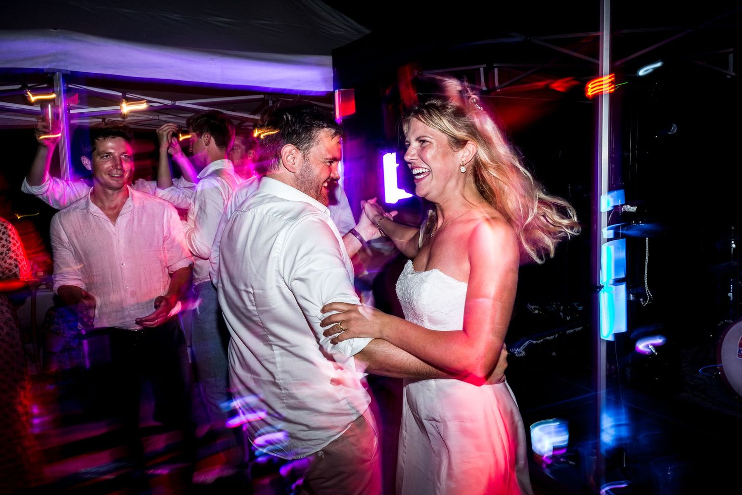 Dance floor filled with party-goers under purple and blue lighting at a nightclub event.