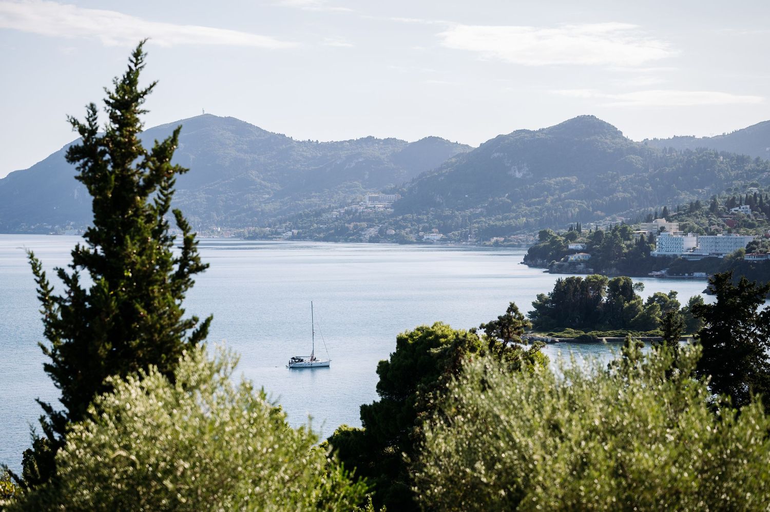 Panoramic view of a coastal mountain landscape with boats dotting the bay.