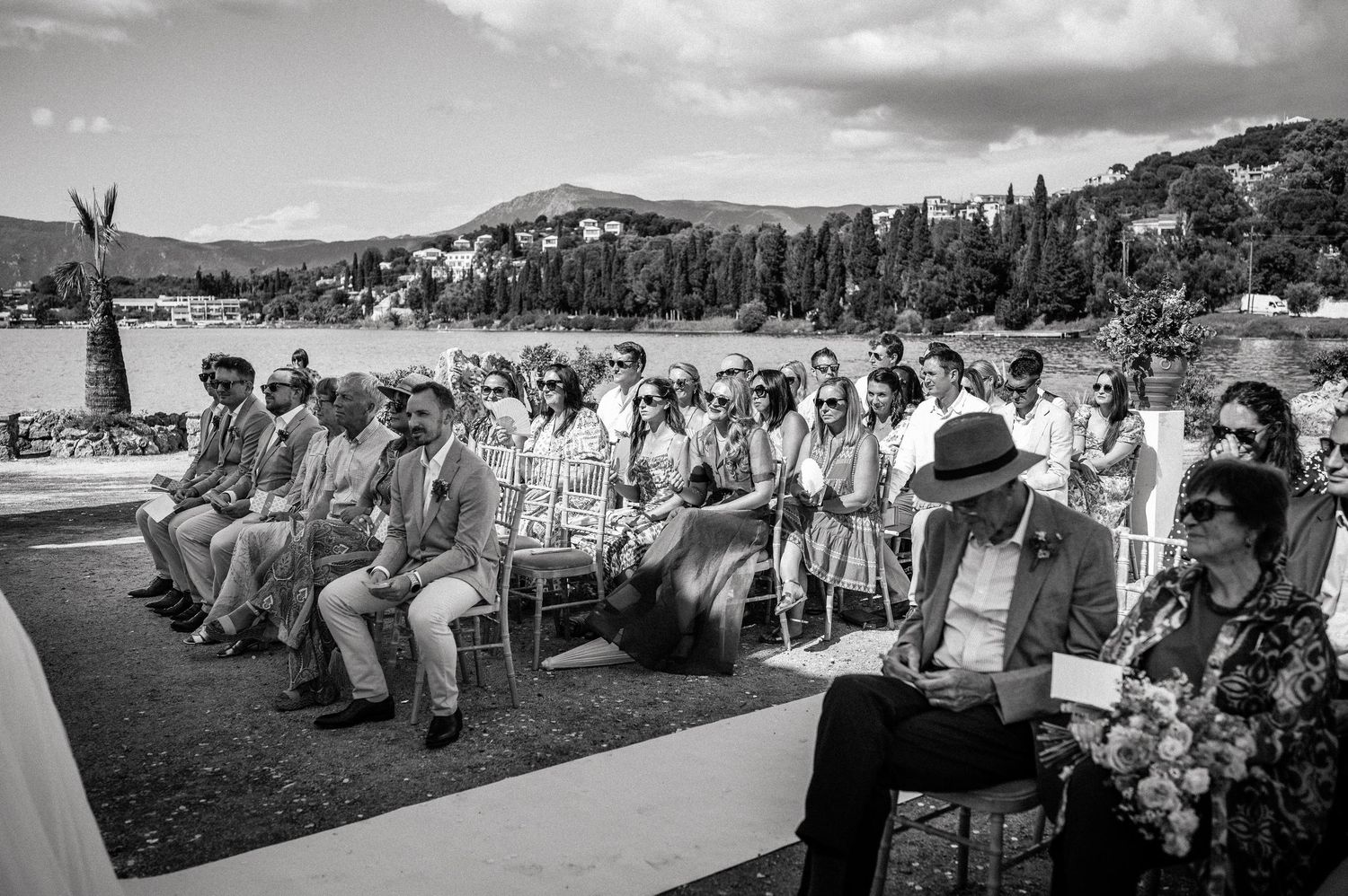 A panoramic black and white view of wedding guests seated outdoors for a ceremony.