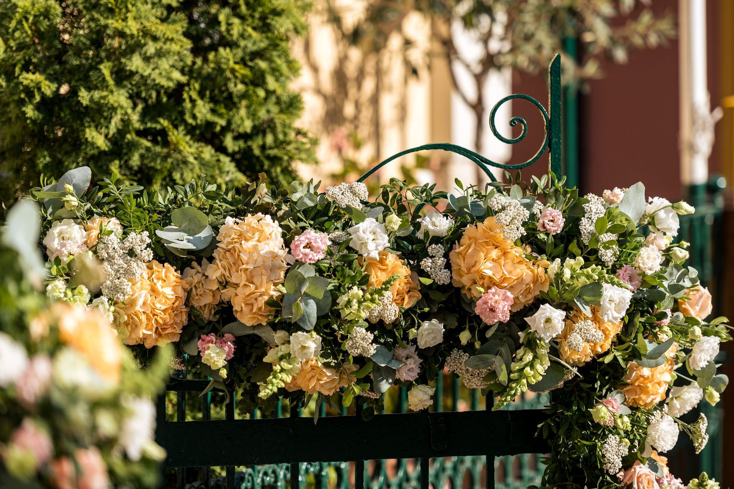 Decorative floral arrangements with peach and cream blooms adorn an outdoor venue.