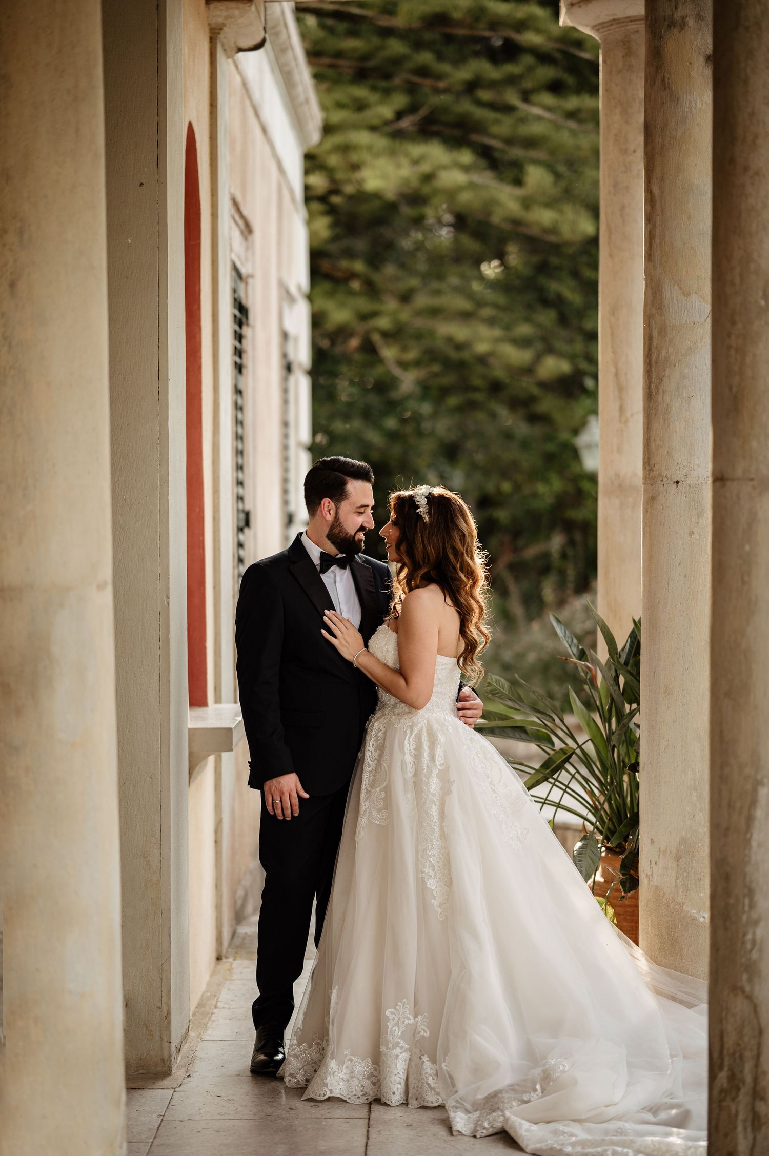 Romantic wedding couple moment captured between elegant stone pillars at sunset.