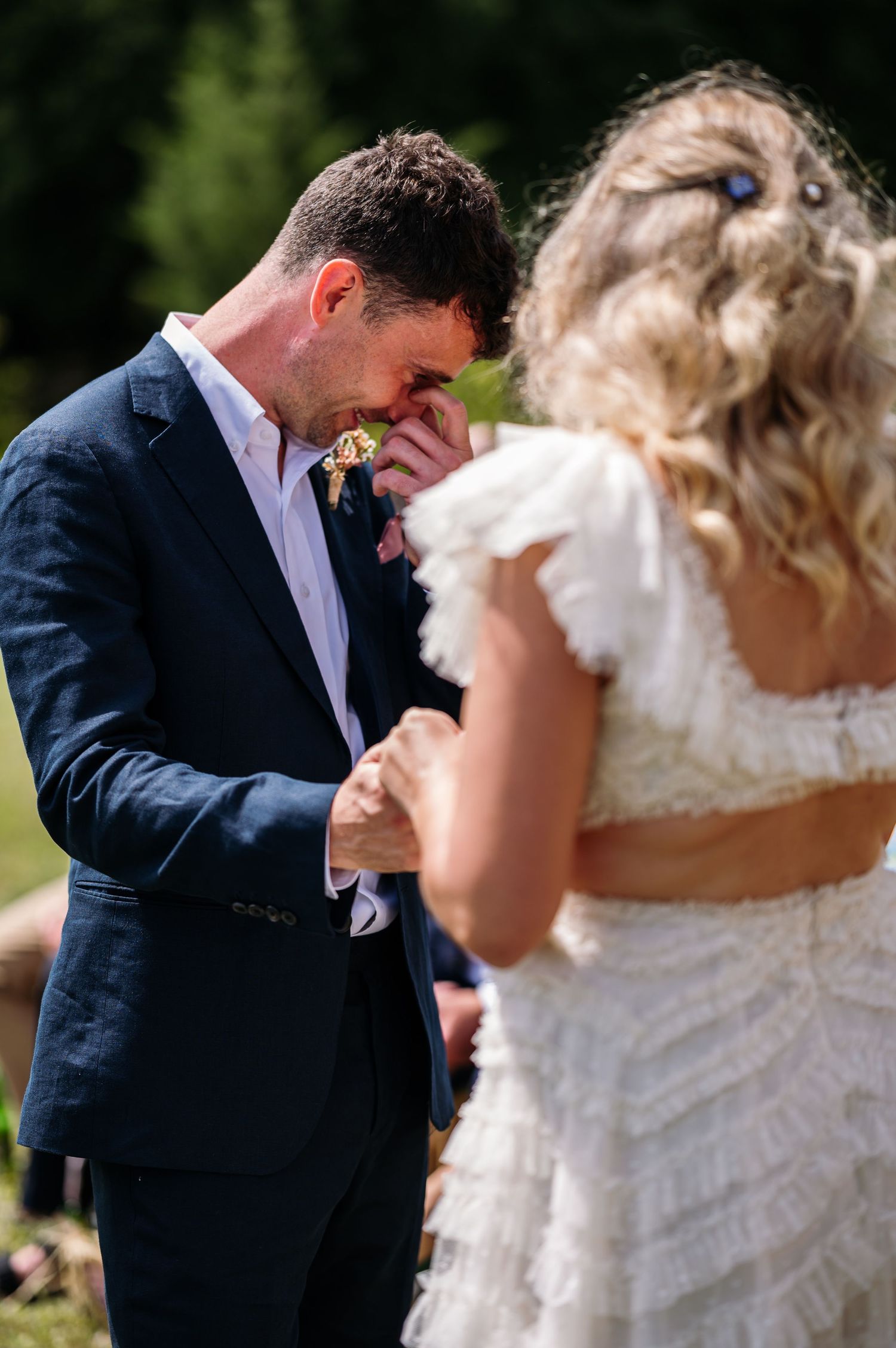 A couple shares a tender moment during their outdoor wedding ceremony in a natural setting.