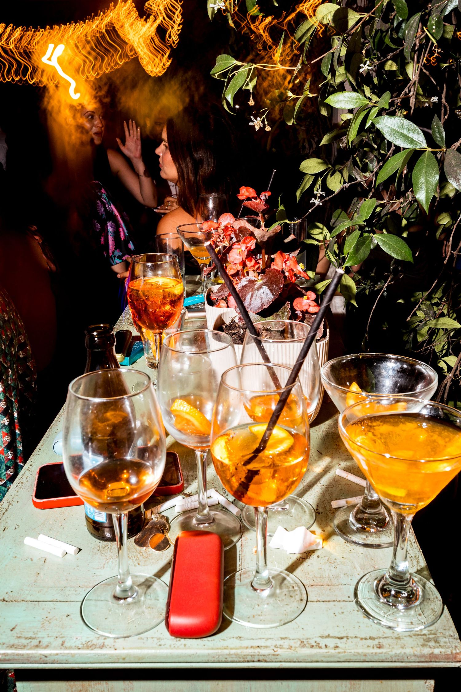 Colorful cocktails in elegant glasses arranged on a rustic surface with ambient lighting and foliage.