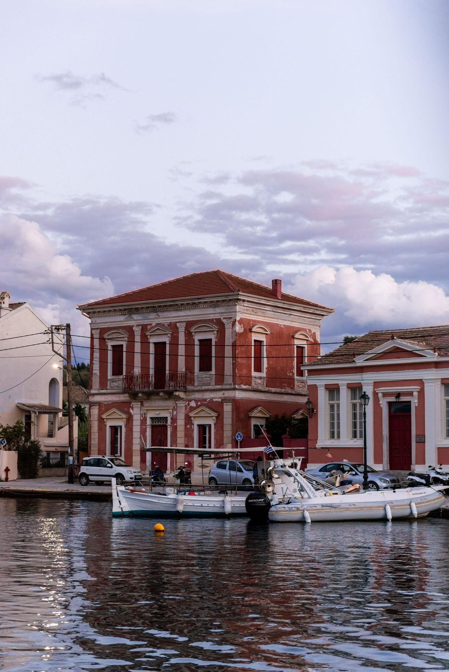 Row of red brick buildings and boats along waterfront marina.