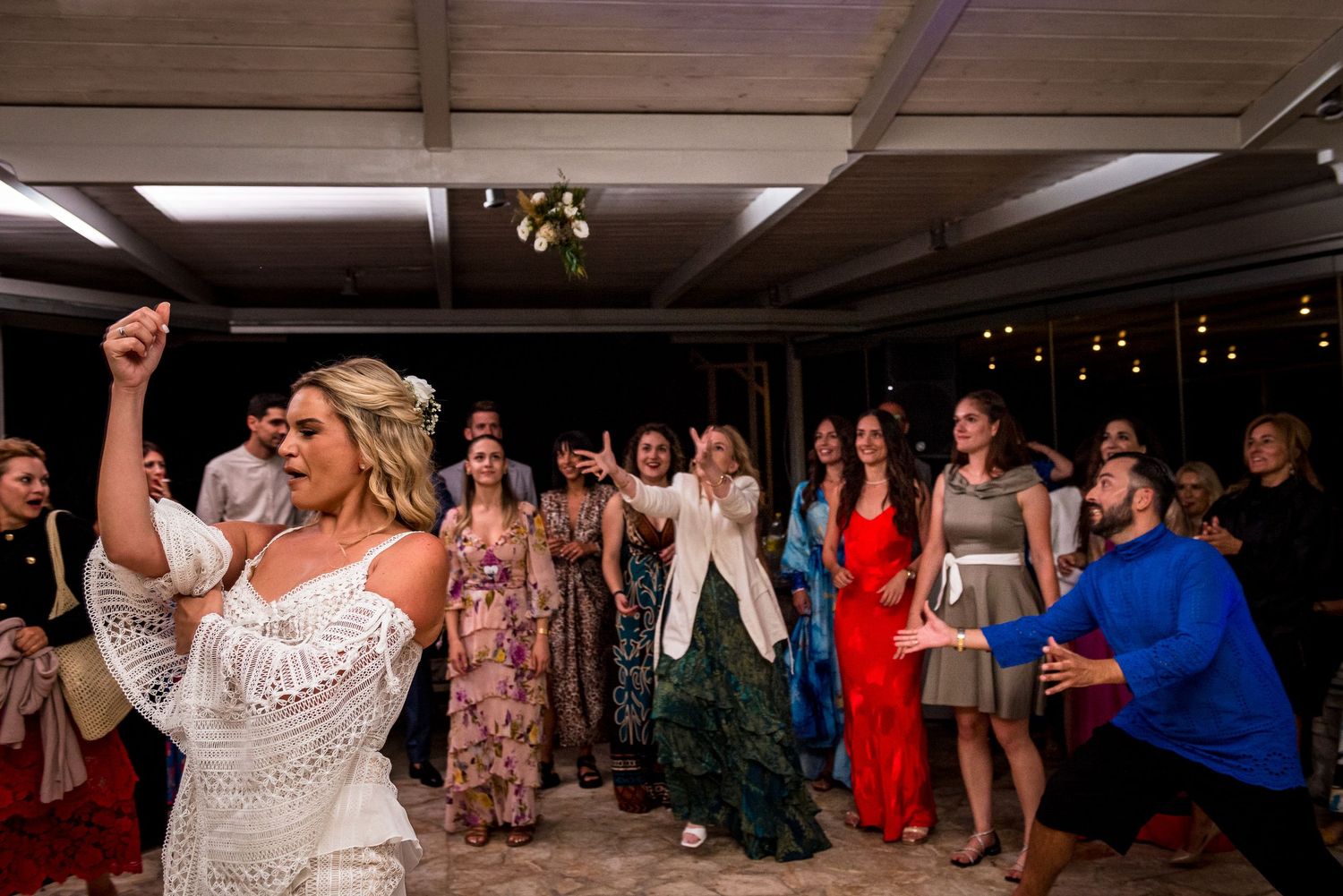 Partygoers raise their arms and dance enthusiastically under indoor venue lighting.