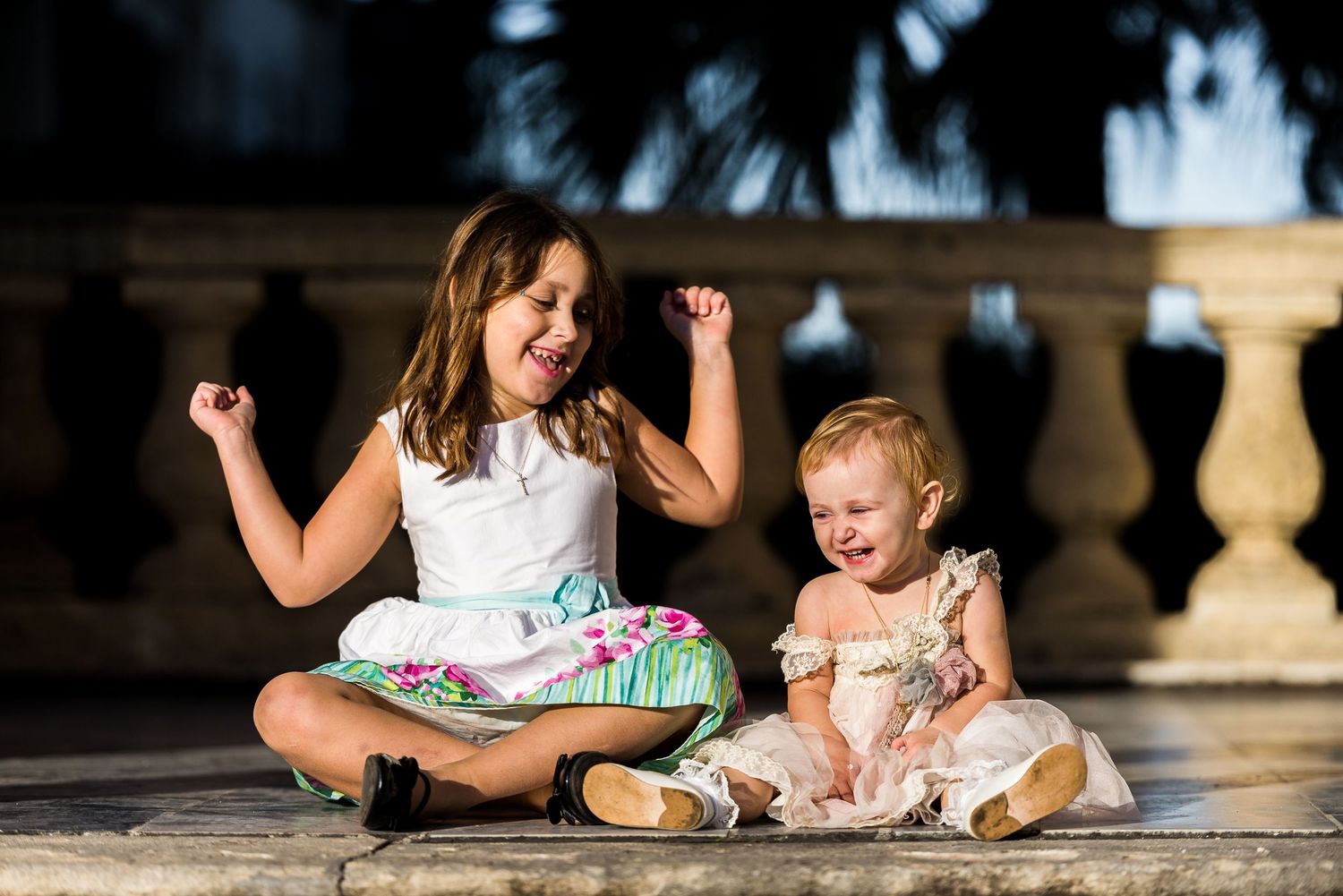 Children sitting on stone steps in formal attire during an outdoor celebration.
