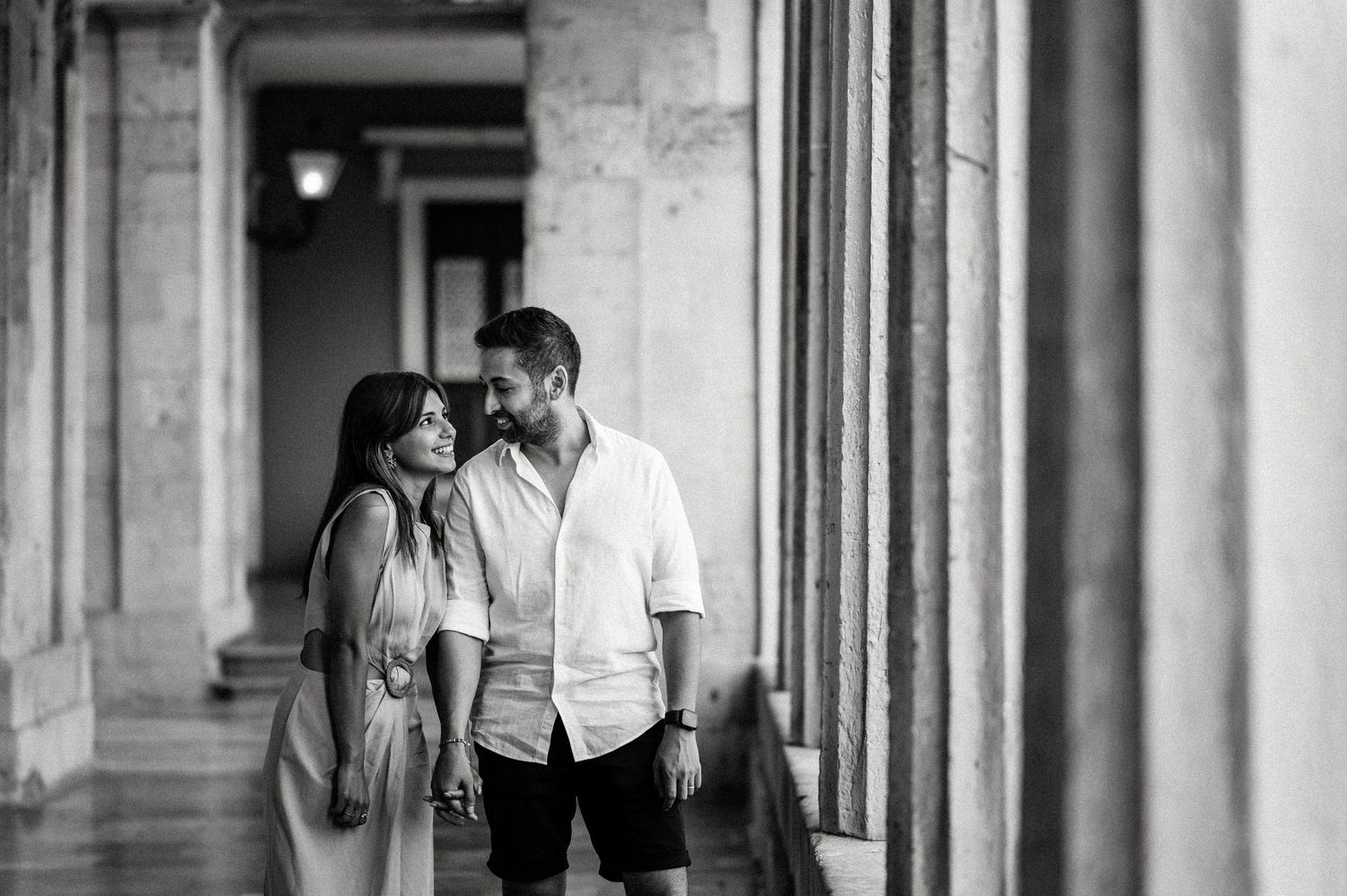 A black and white moment captured in an elegant corridor with classical architecture.