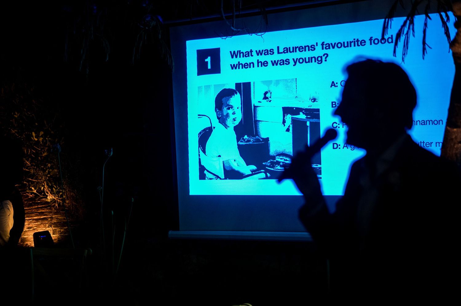 Silhouettes of guests watching a presentation against a blue-lit screen.