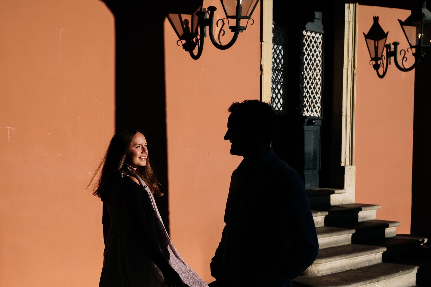 Dramatic shadows and silhouettes cast on a coral-colored wall in natural light.