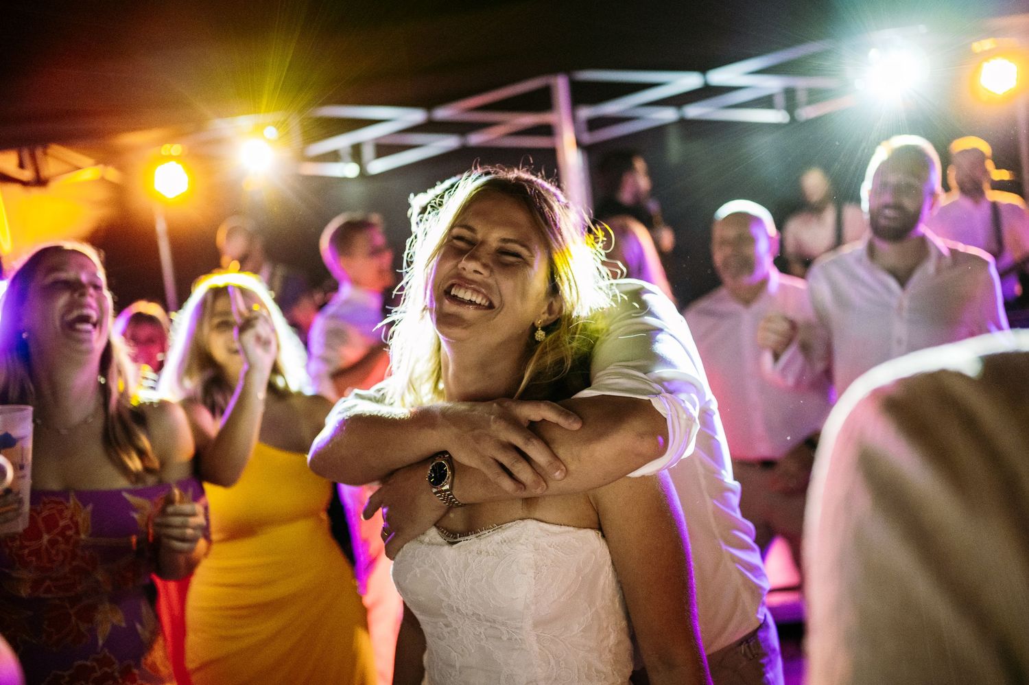 Joyful celebration on a dance floor with colorful party lighting creating festive atmosphere.