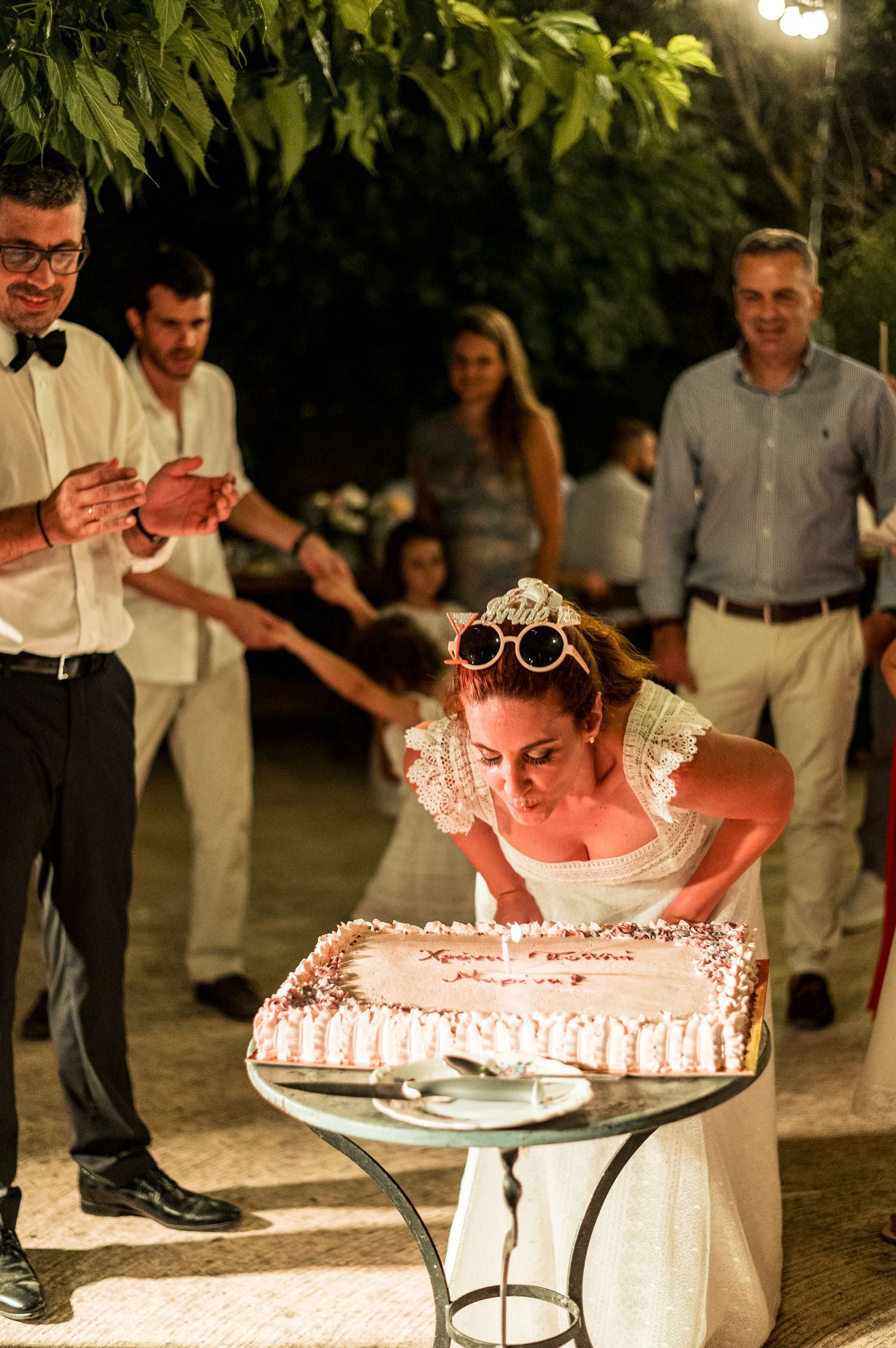 Wedding reception scene showing a traditional cake-cutting moment outdoors at night.