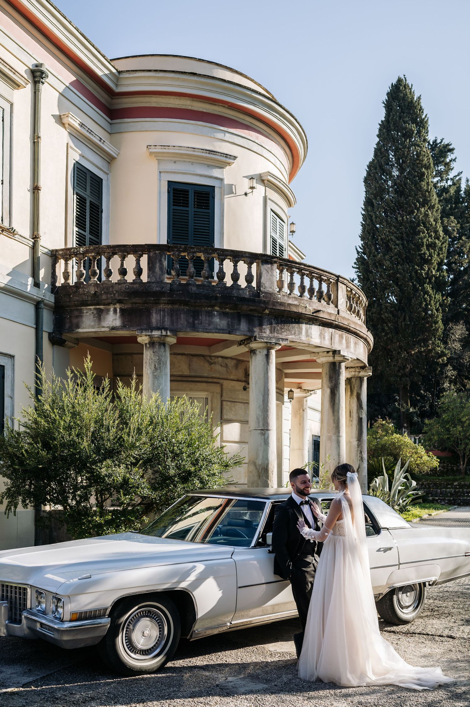 Elegant silver vintage Cadillac parked outside a grand Italian villa during a wedding photoshoot.