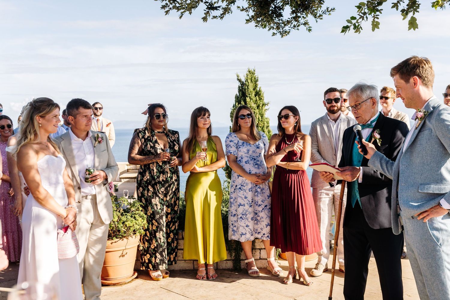 Outdoor wedding celebration with guests mingling and socializing in colorful summer attire.