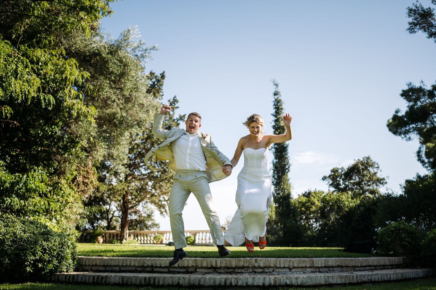 Wedding couple playfully poses in lush garden setting during photo session.