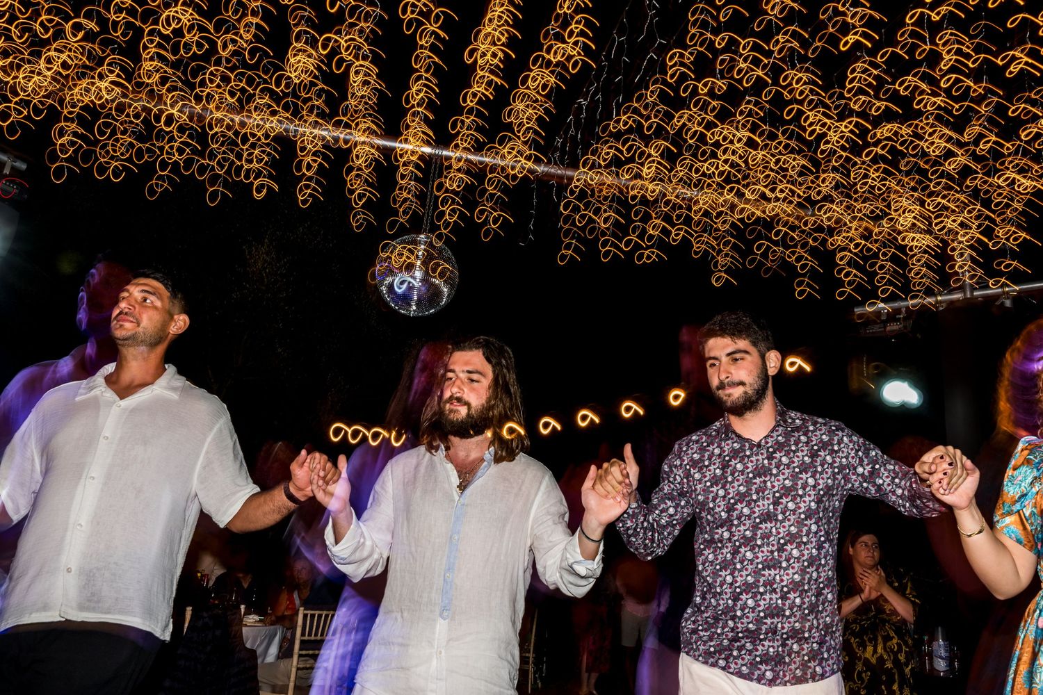 Guests form a dancing chain at nighttime wedding celebration.