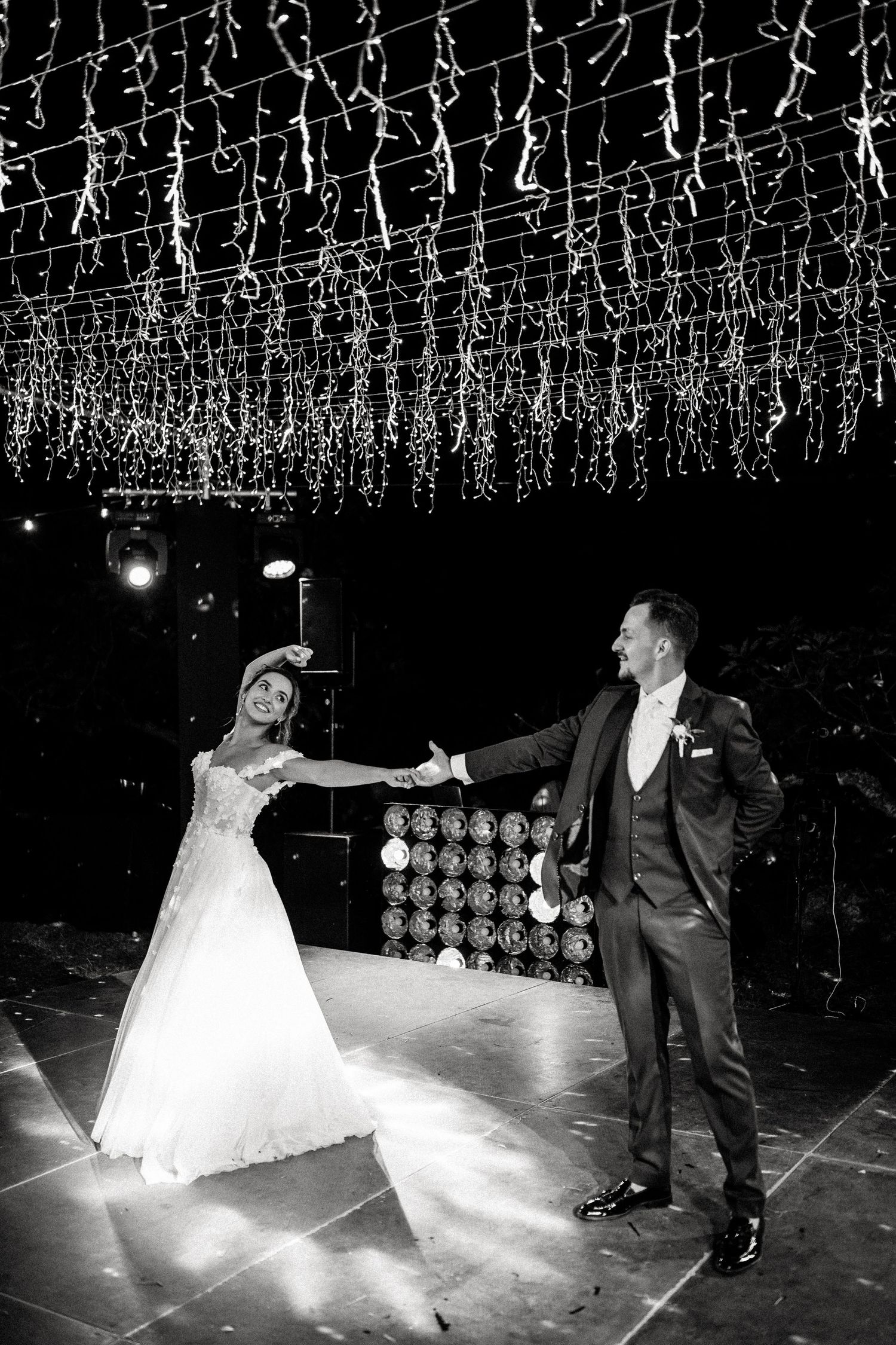 Wedding couple performs dramatic dance moves on illuminated dance floor.