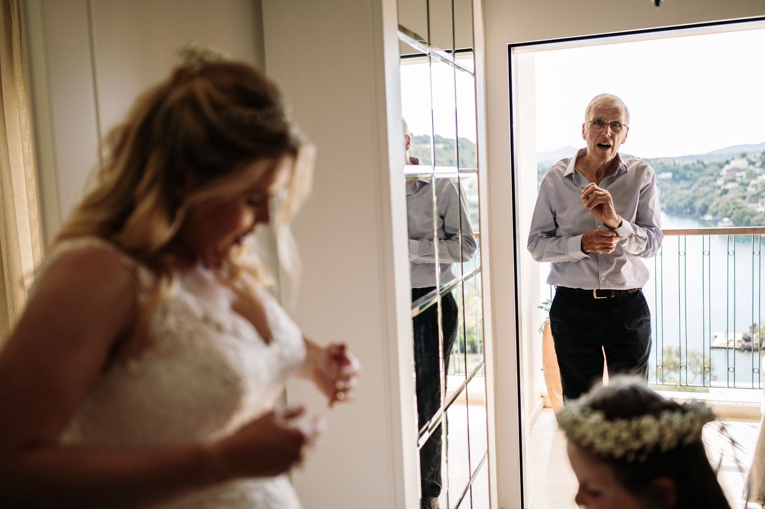 Wedding preparation moment captured through doorway with ocean view in background.