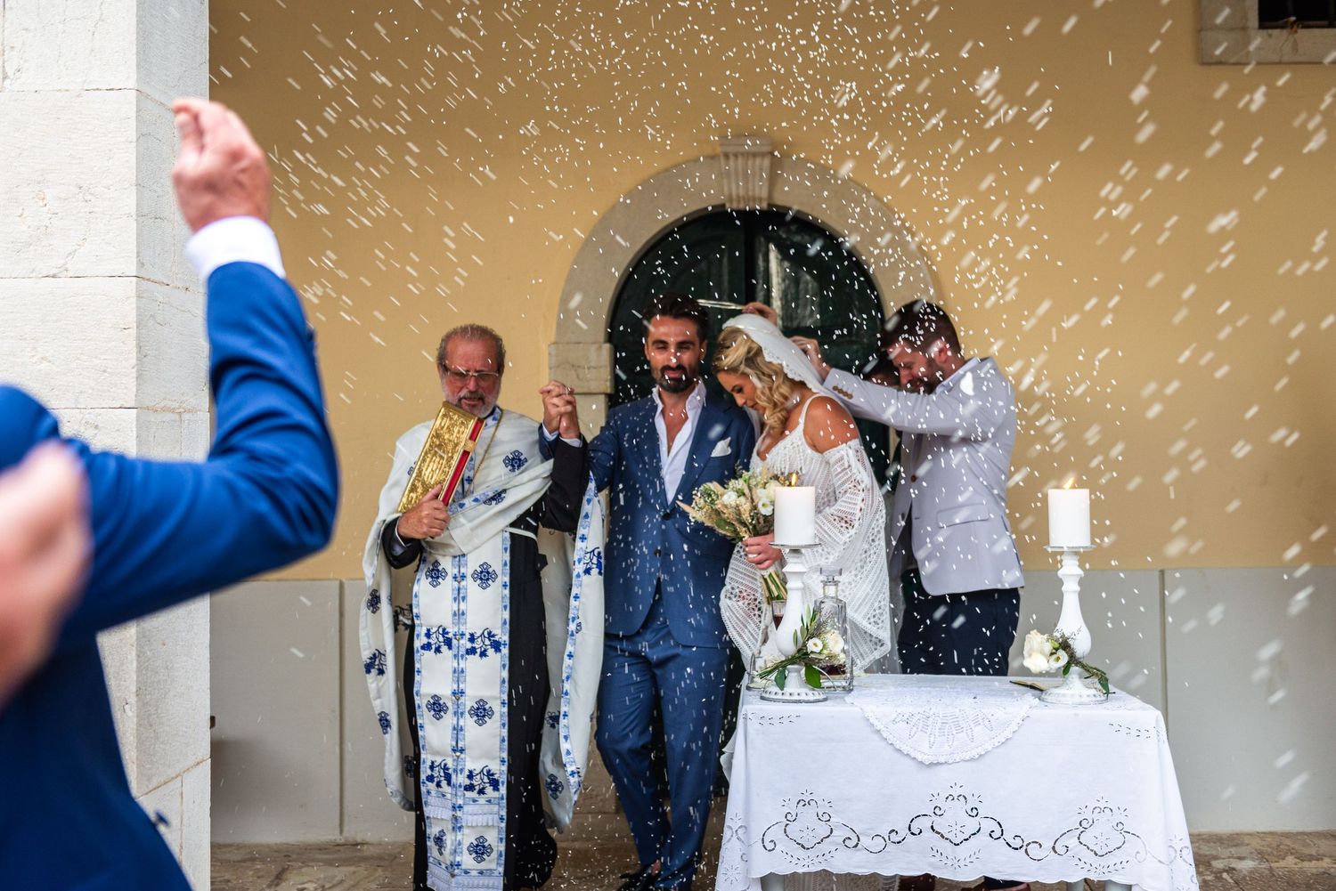 Wedding guests celebrating with confetti and rice toss outdoors.