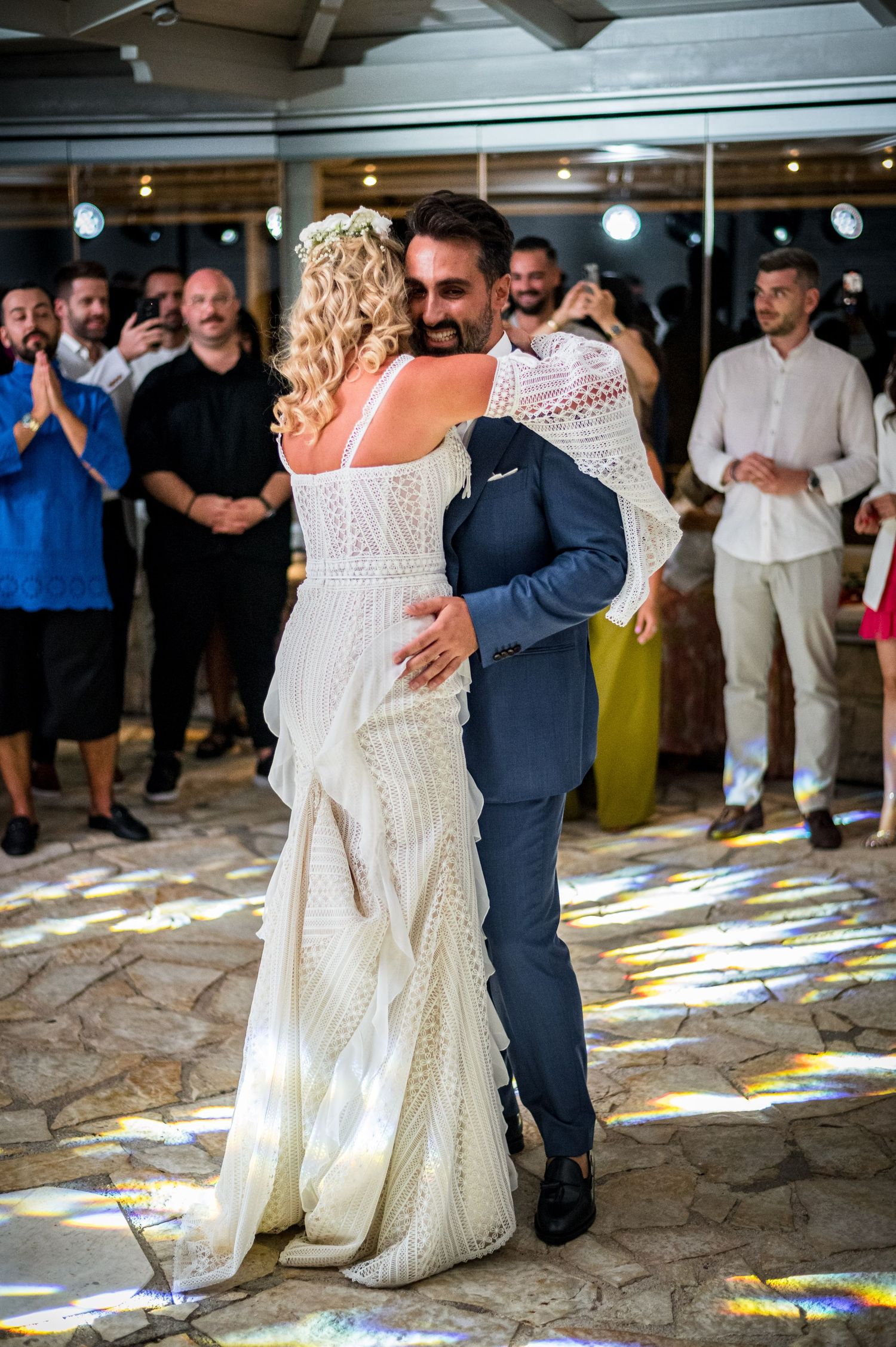 Wedding couple dances on colorful tiled floor surrounded by guests.