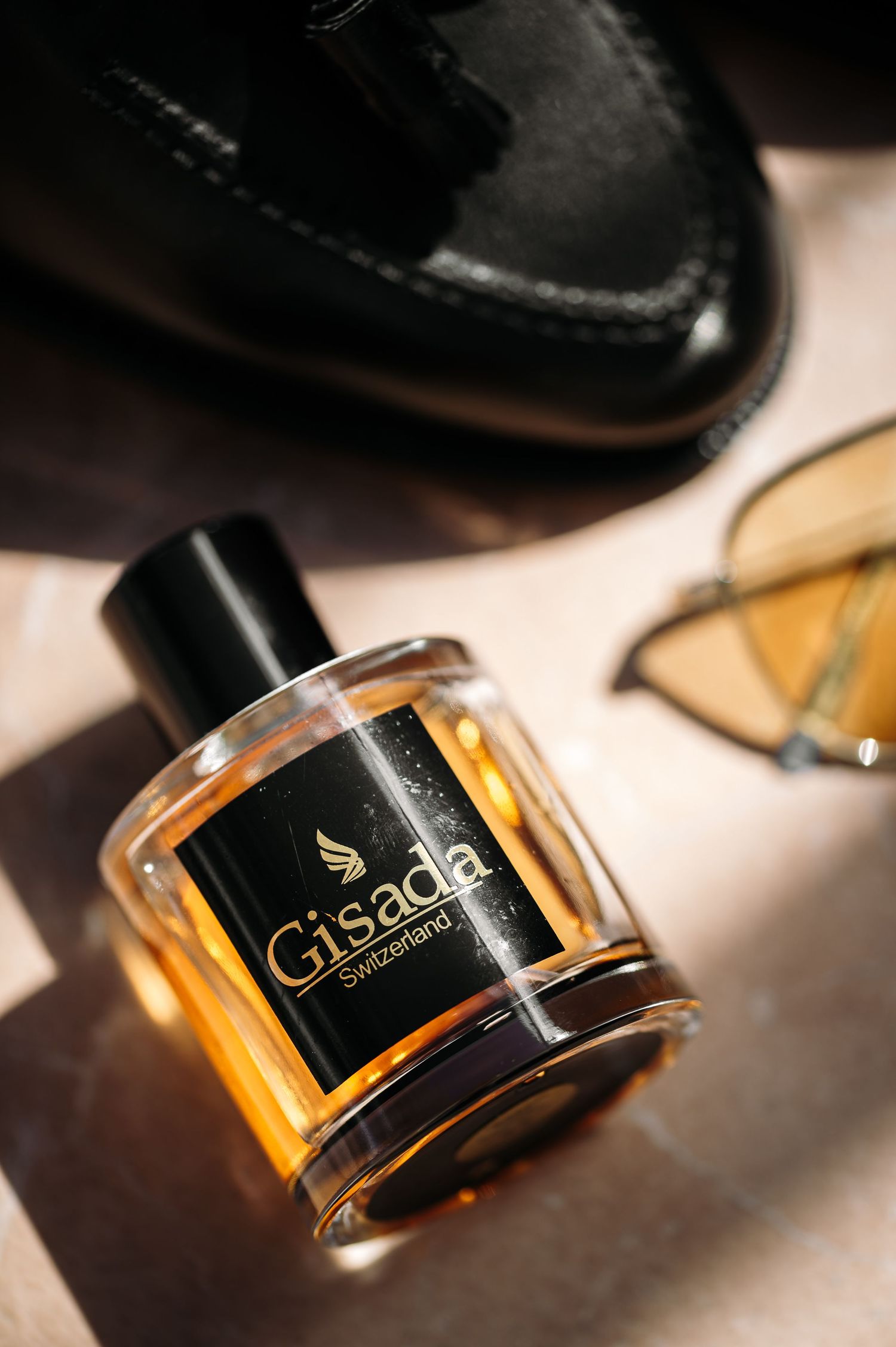 Elegant bottle of Gisada perfume with amber liquid photographed with dramatic lighting.