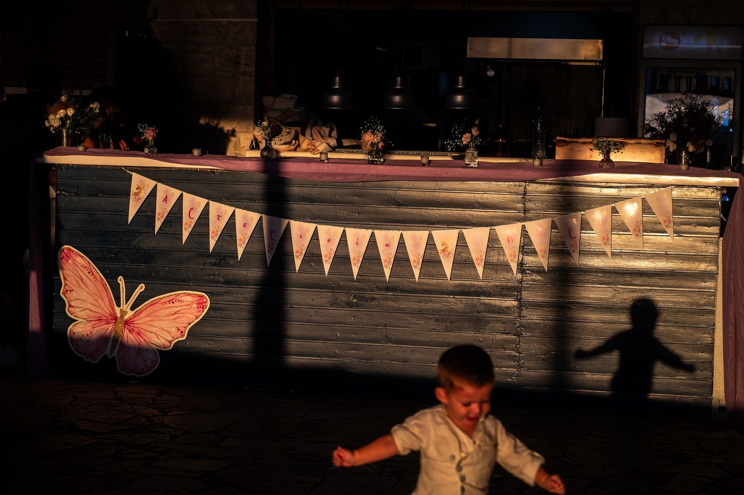 Festive party scene with bunting flags and orange butterfly decoration in evening light.
