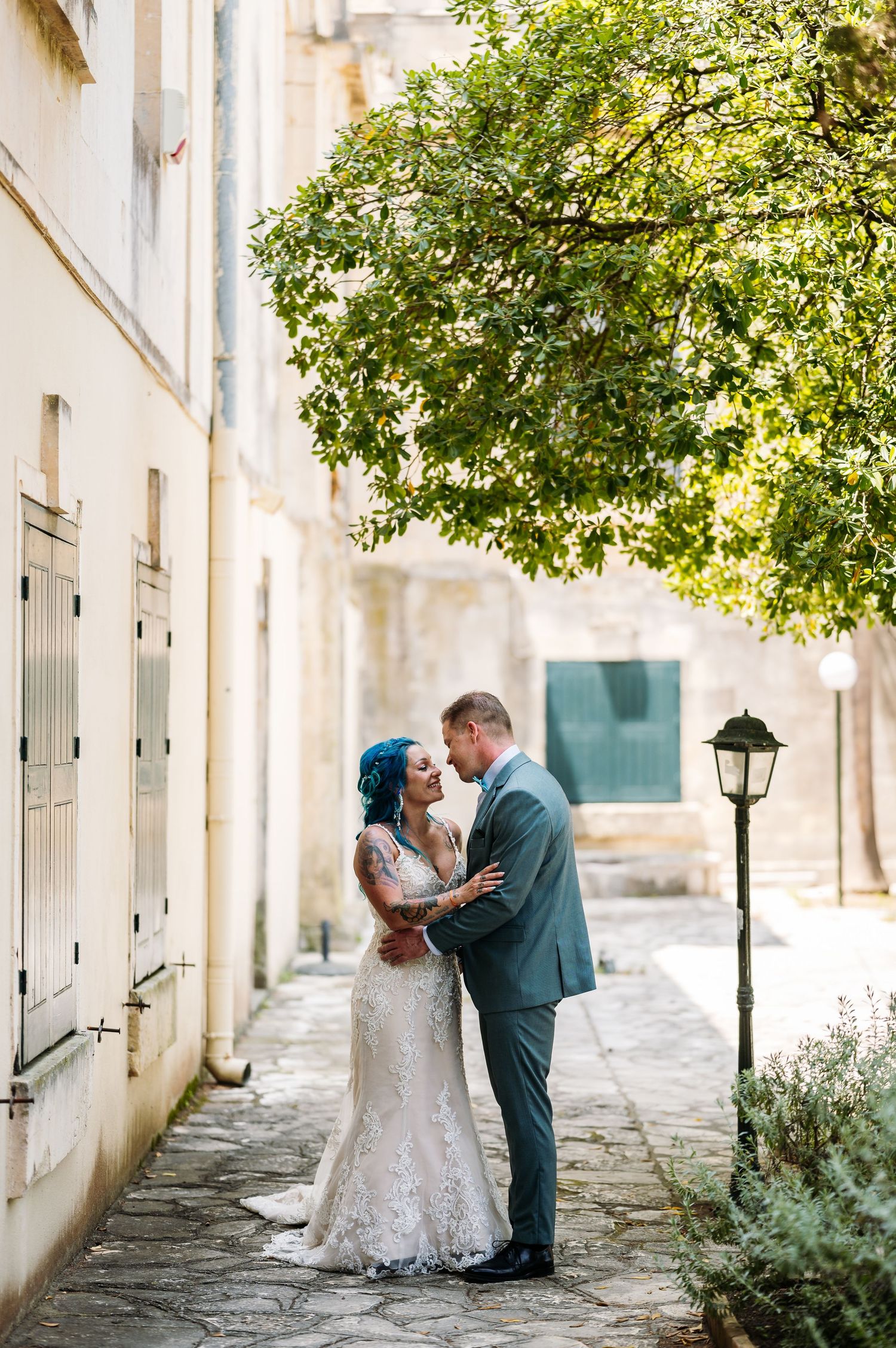 Romantic wedding portraits along a sunlit colonnade with greenery.