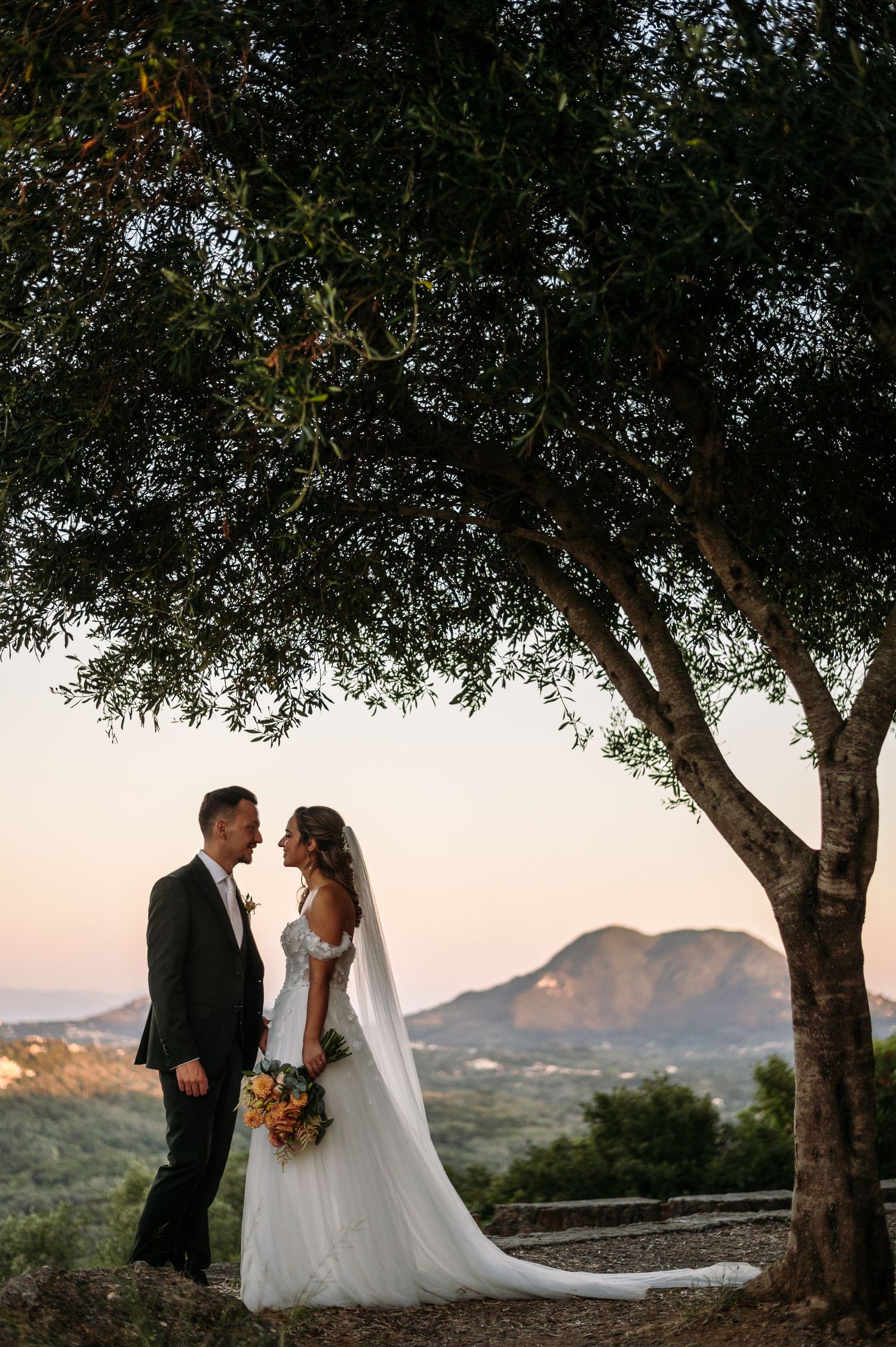 Romantic sunset wedding portraits under oak trees with mountain views in background.