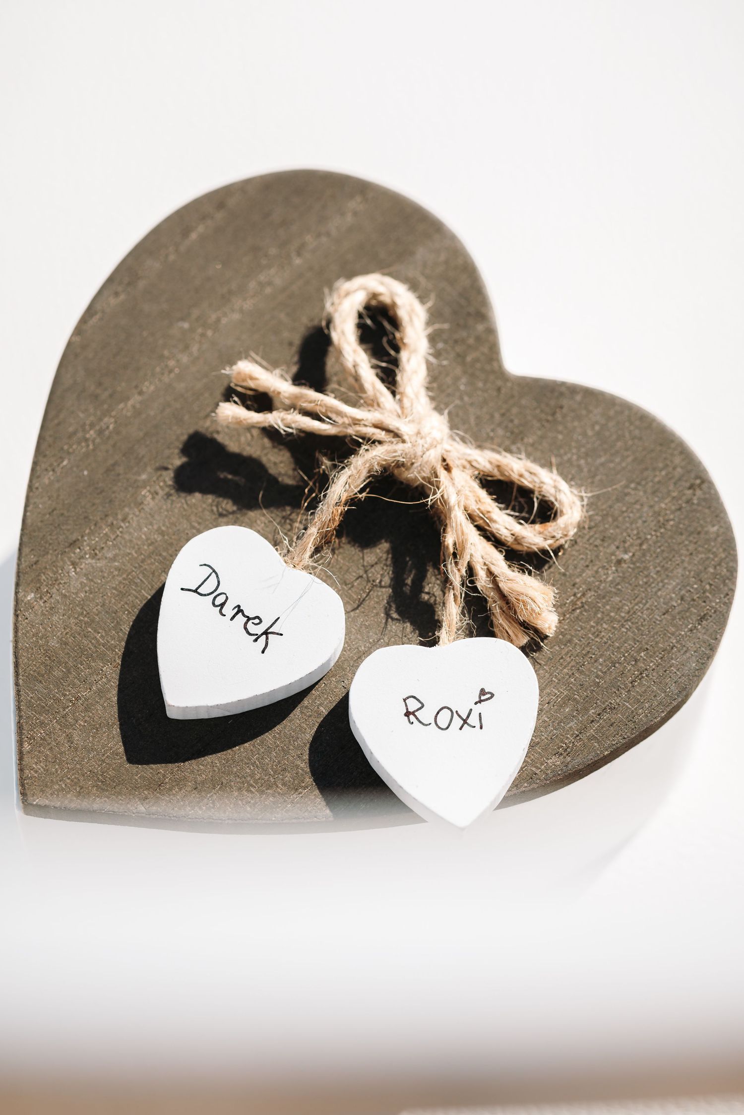 Decorative heart shapes with names written on them tied with rustic twine.