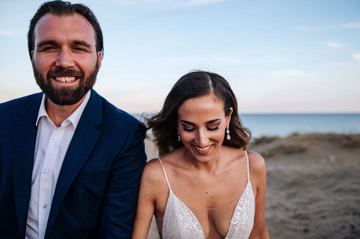 Joyful wedding couple shares tender moments on sandy beach at sunset.