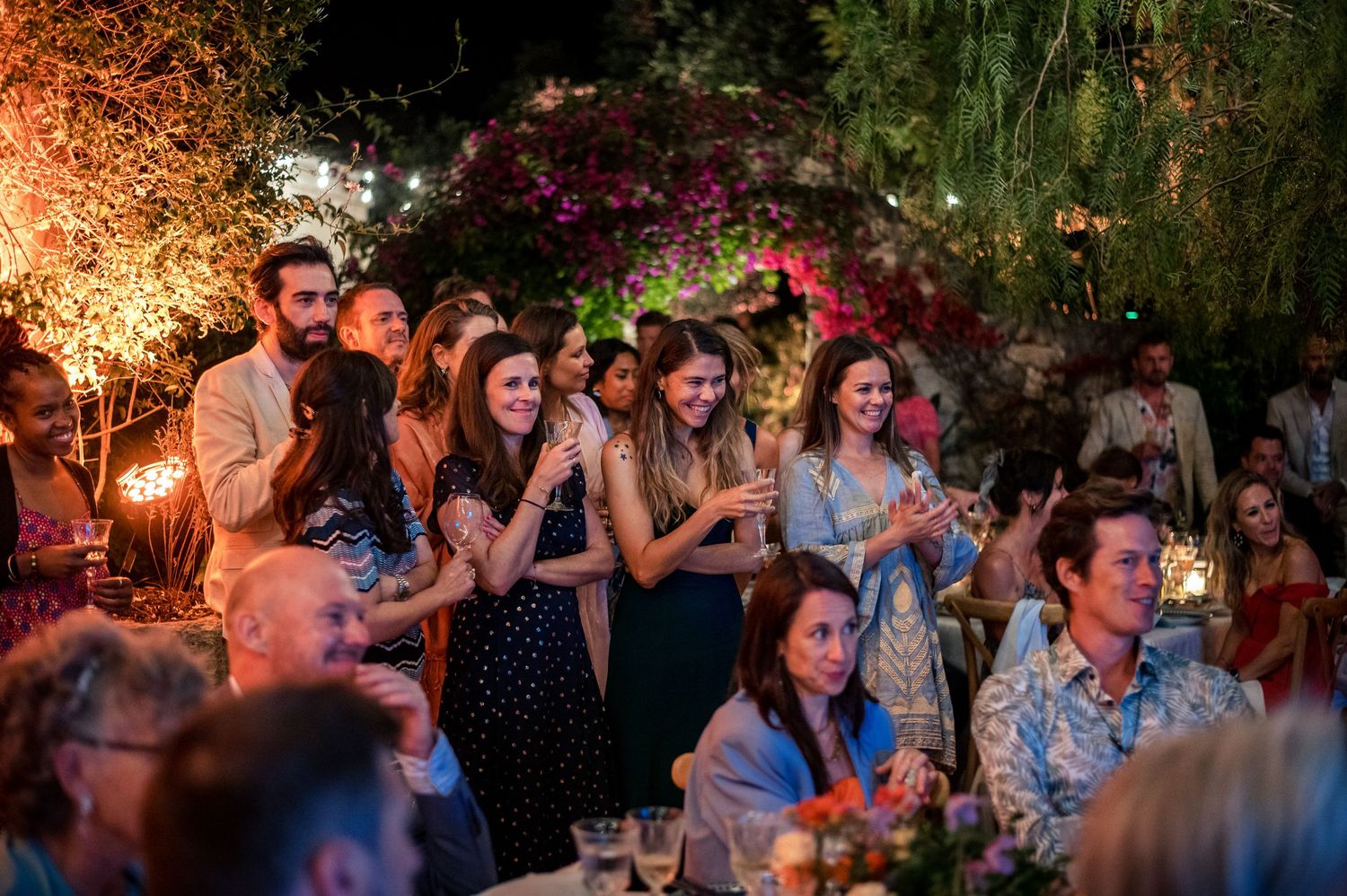 Wedding reception guests enjoying an evening celebration under warm lighting.