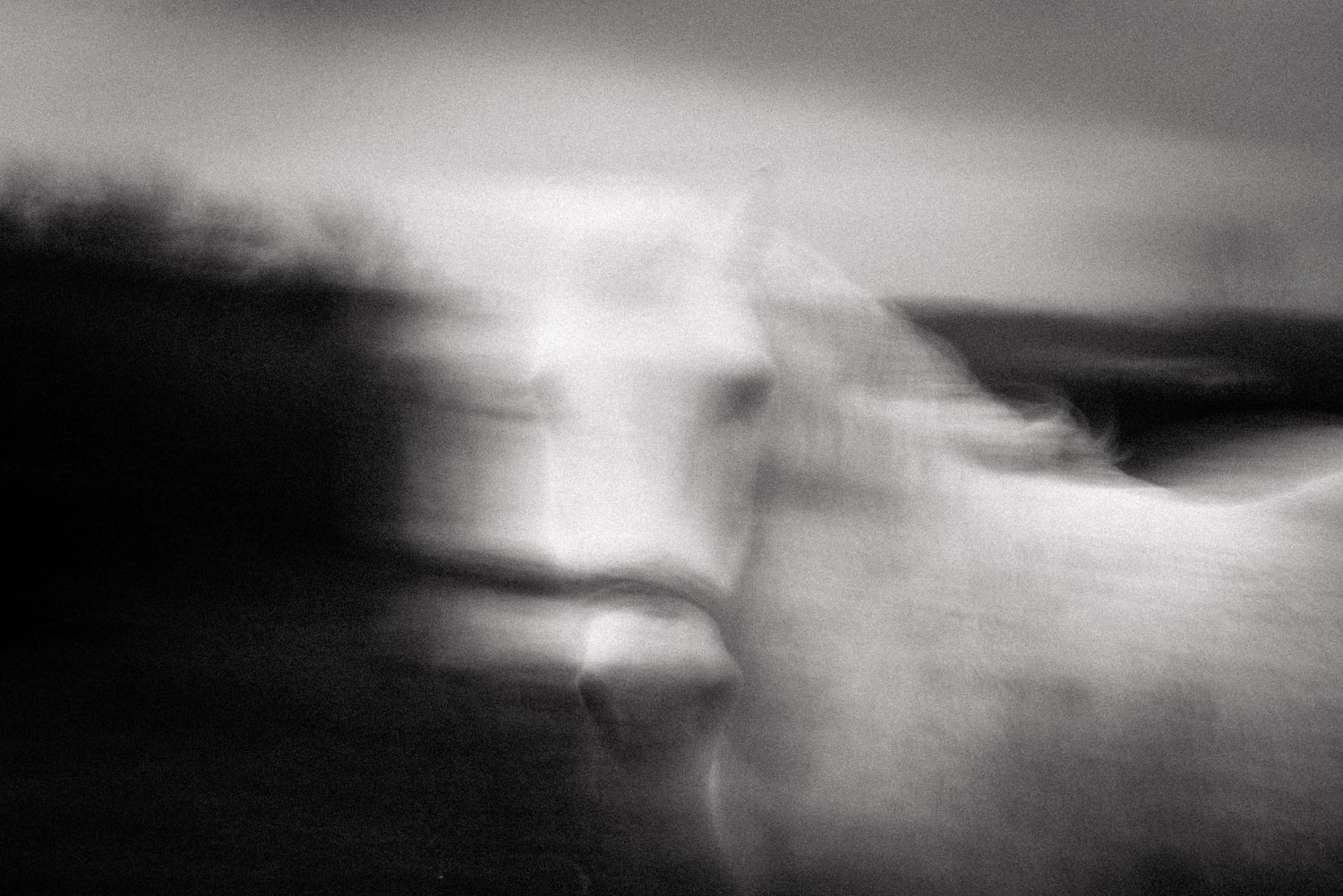 Abstract black and white landscape with blurred motion and atmospheric elements.