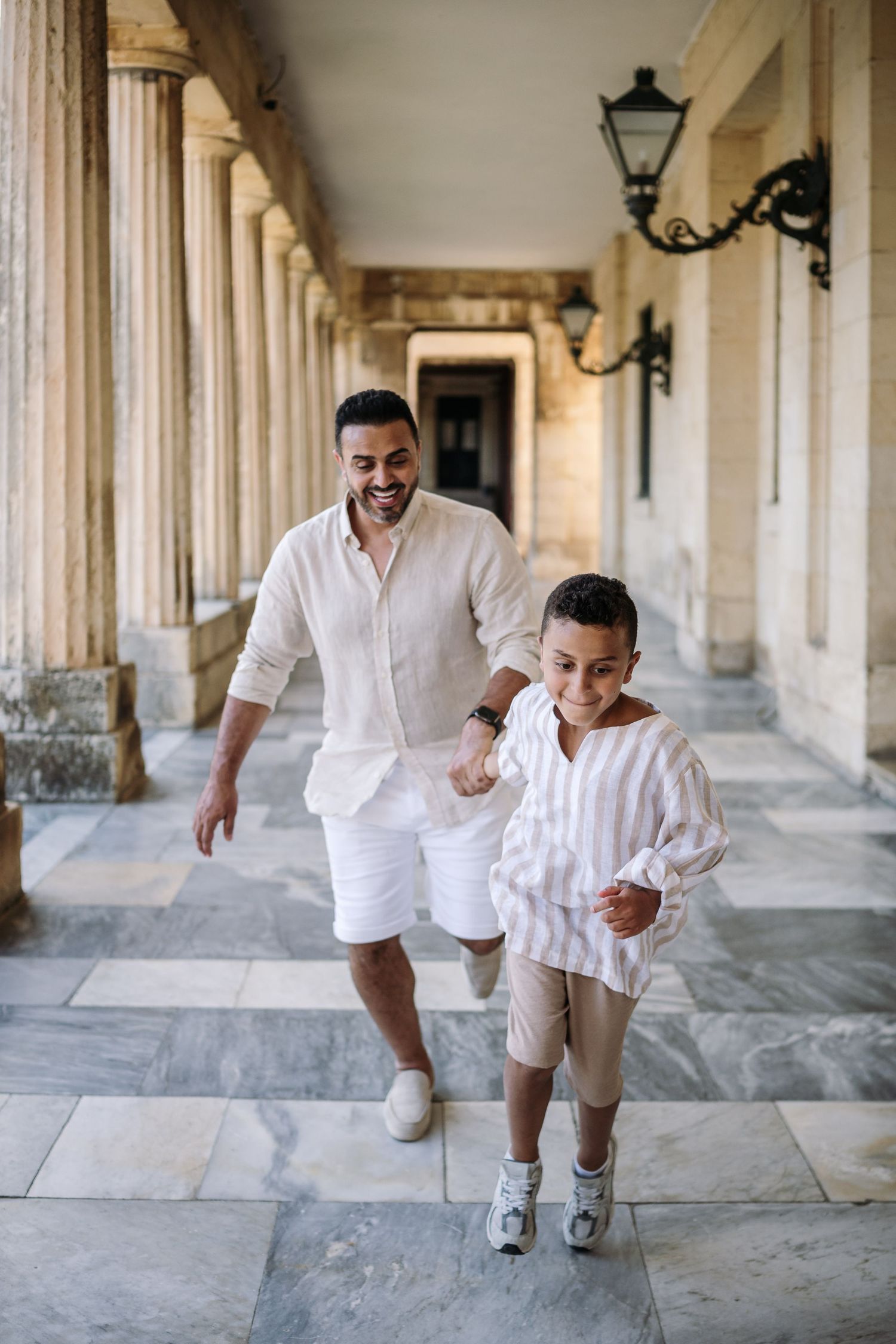 Playful moments captured between parent and child running through a grand colonnade.