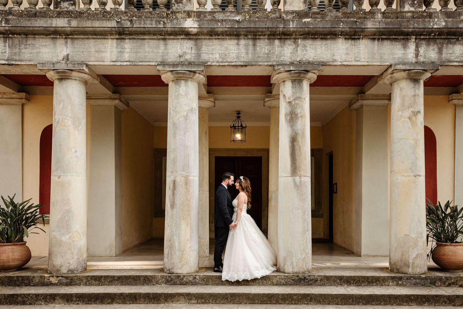 Wedding photography session in a classical colonnade with stone pillars and arches.