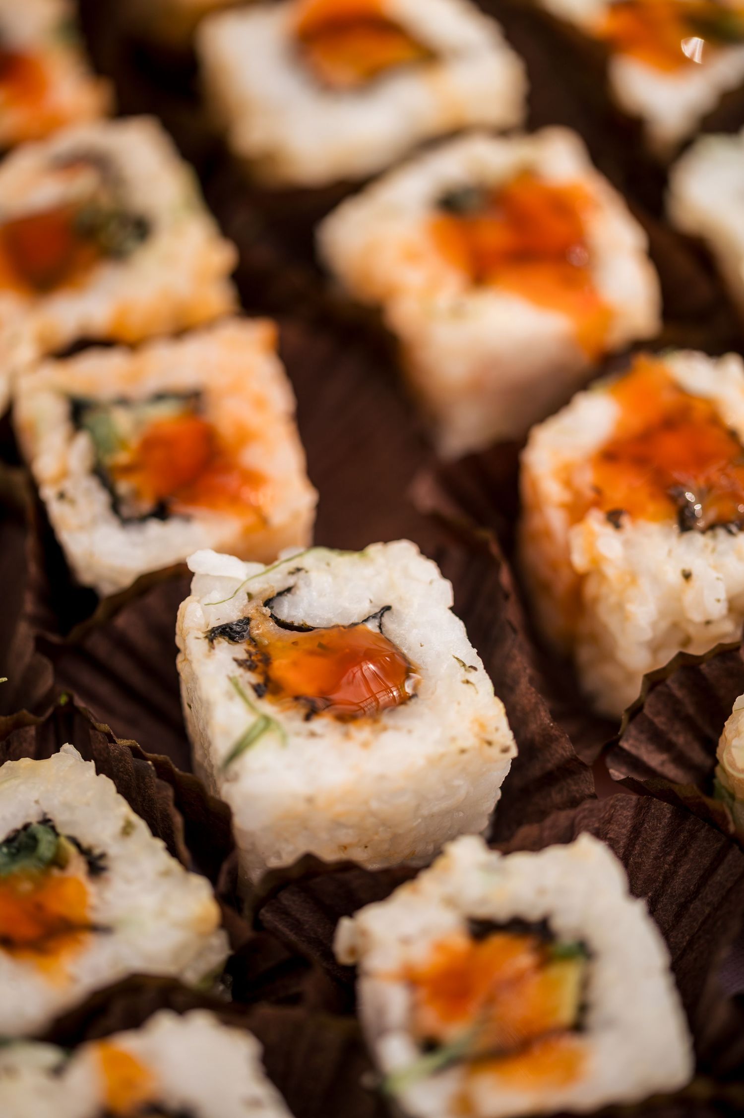Close-up of beautifully plated sushi rolls with orange toppings.