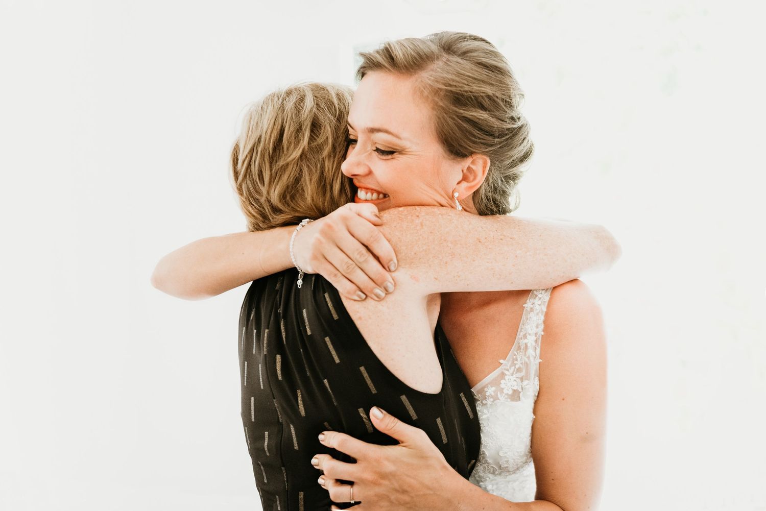 Intimate wedding moments captured in soft white tones showing embraces and emotions.