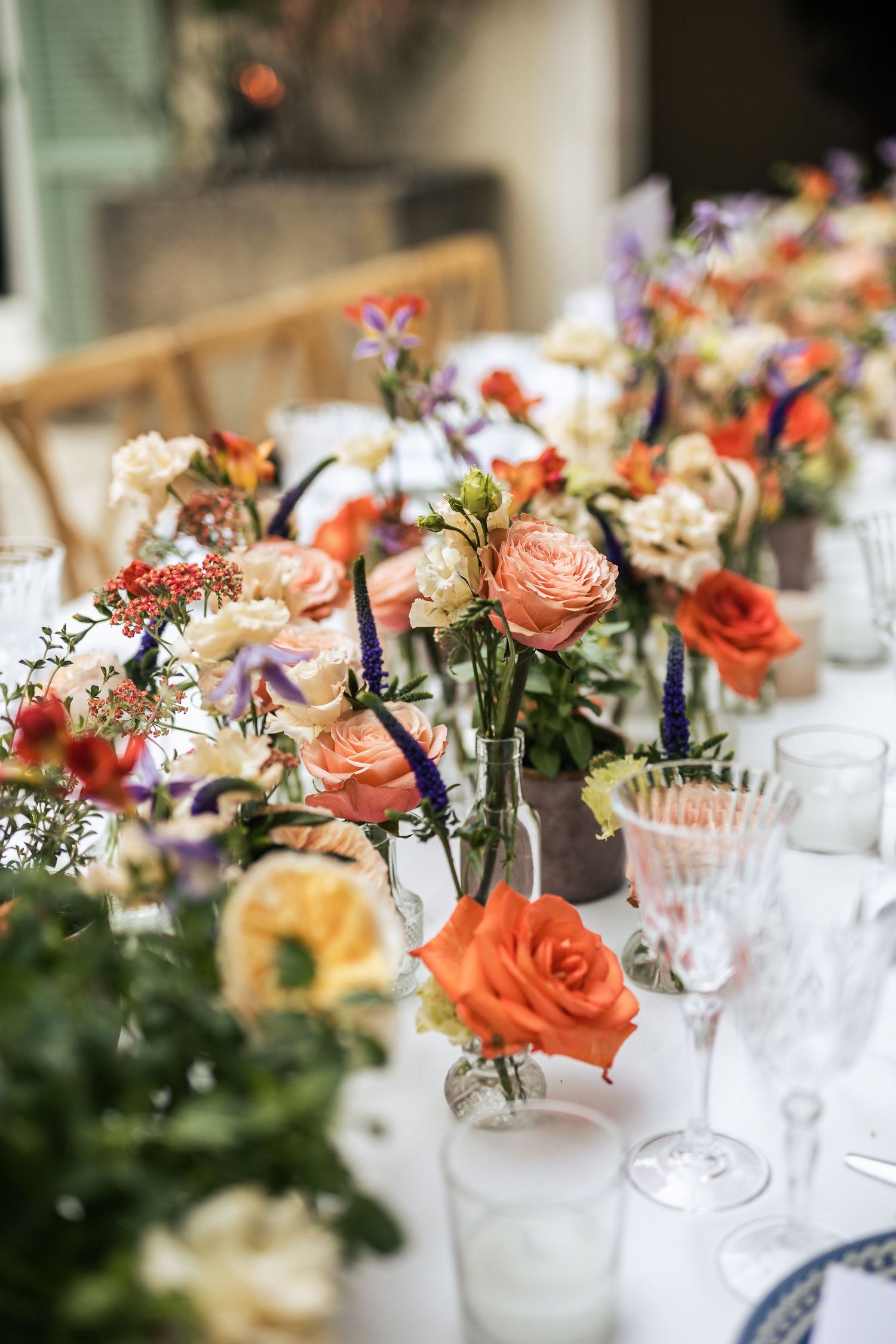 Elegant table settings with coral and peach floral centerpieces and crystal glassware.