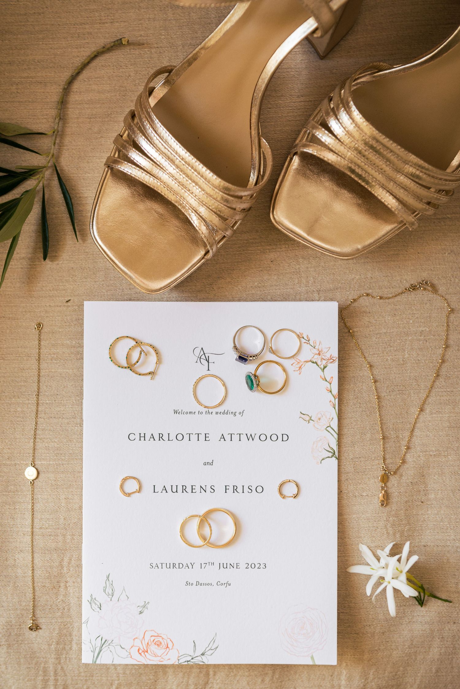 Wedding invitation with gold rings and floral design elements on wooden surface.