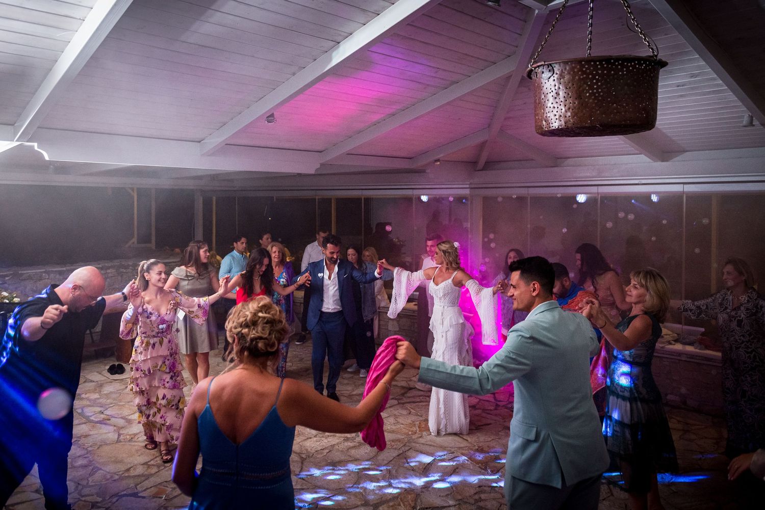 Wide angle view of a wedding reception dance floor with pink accent lighting.