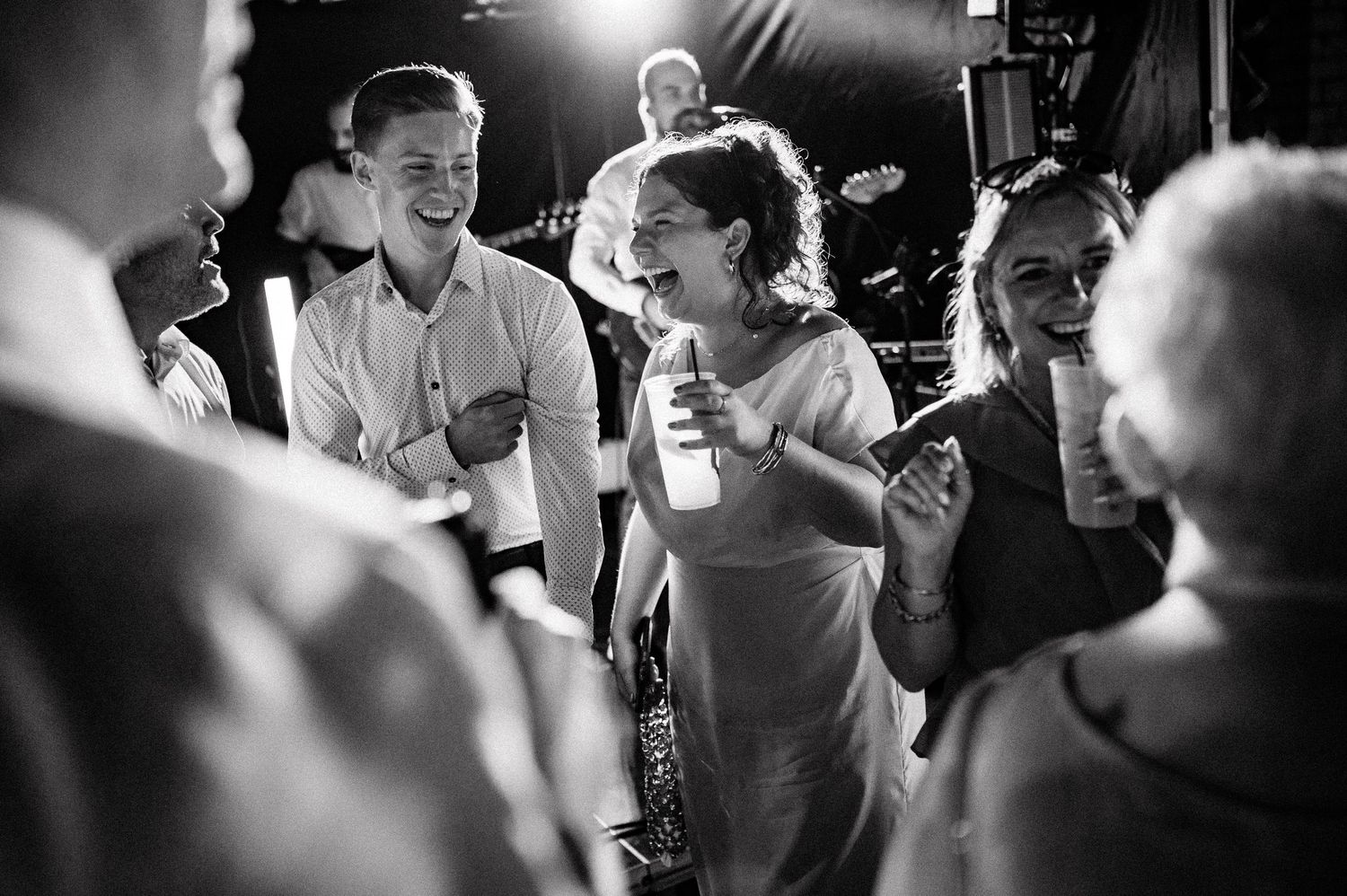 Black and white candid shot of wedding guests laughing and celebrating together.